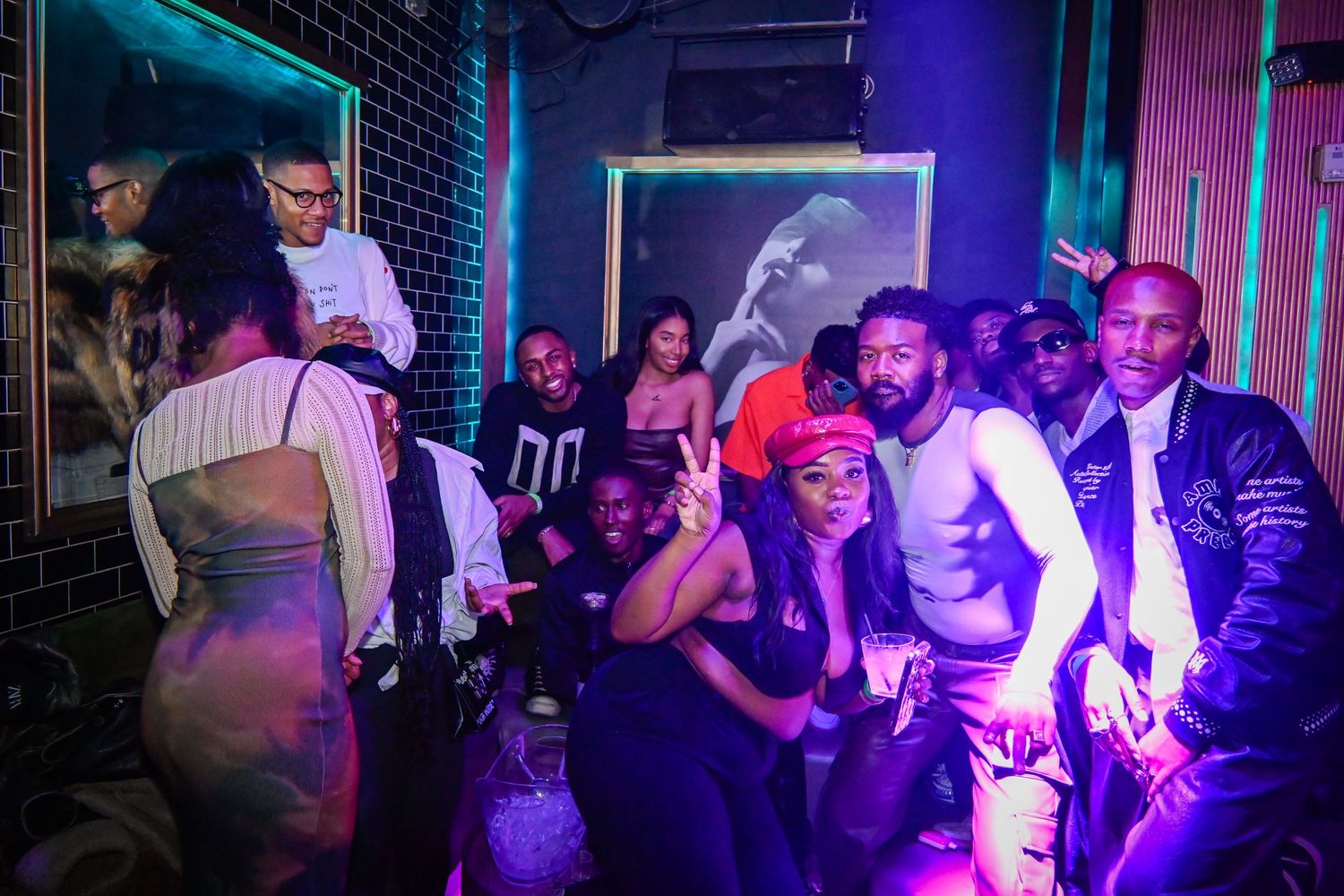 A group of people dancing and socializing at a nightclub with purple and blue lighting creating a vibrant atmosphere.