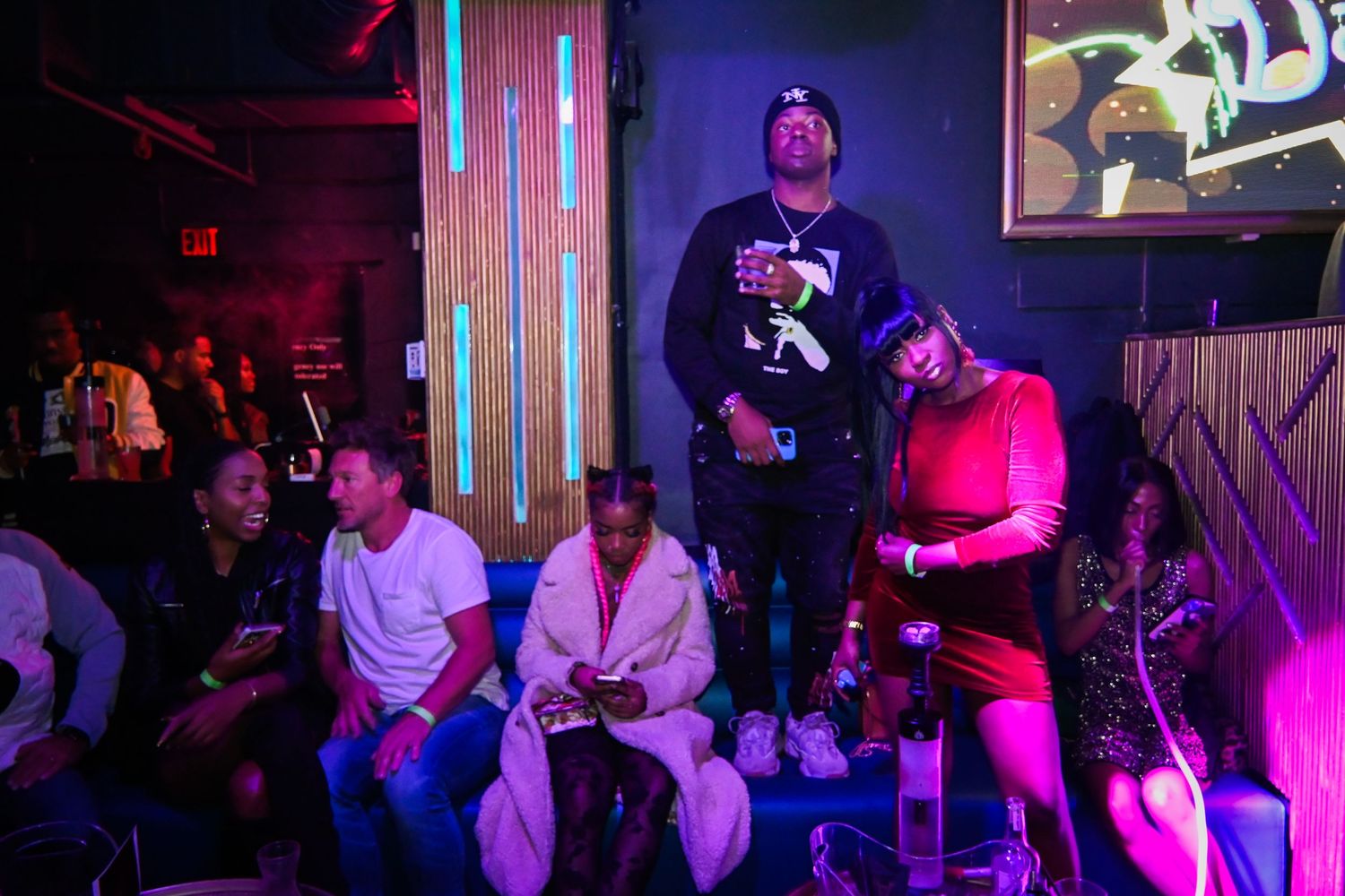 A group performs on stage in a dark venue with purple and red lighting creating a dramatic atmosphere.