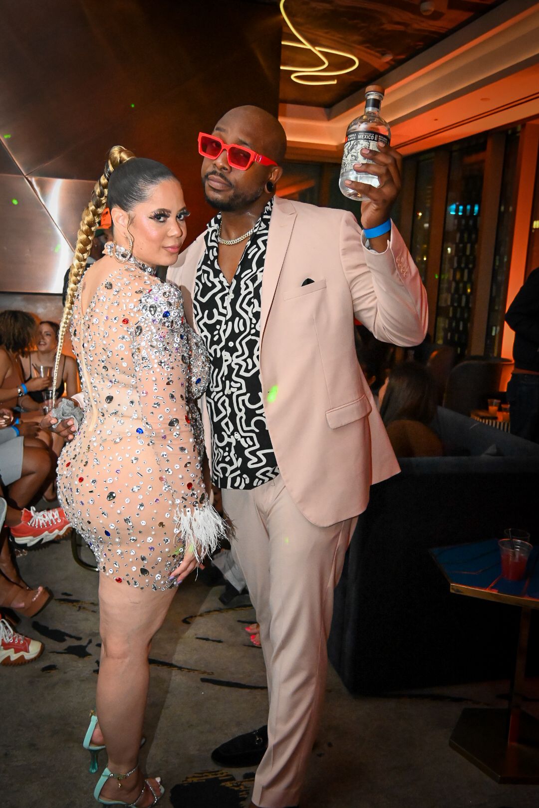Two people dancing at an event, one wearing a sparkly peach dress and the other in a light pink suit.
