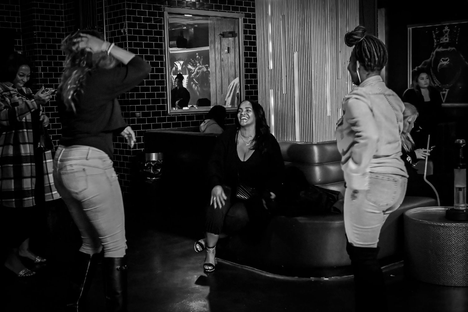 A series of black and white photos showing people dancing and socializing in a dimly lit bar or nightclub setting.