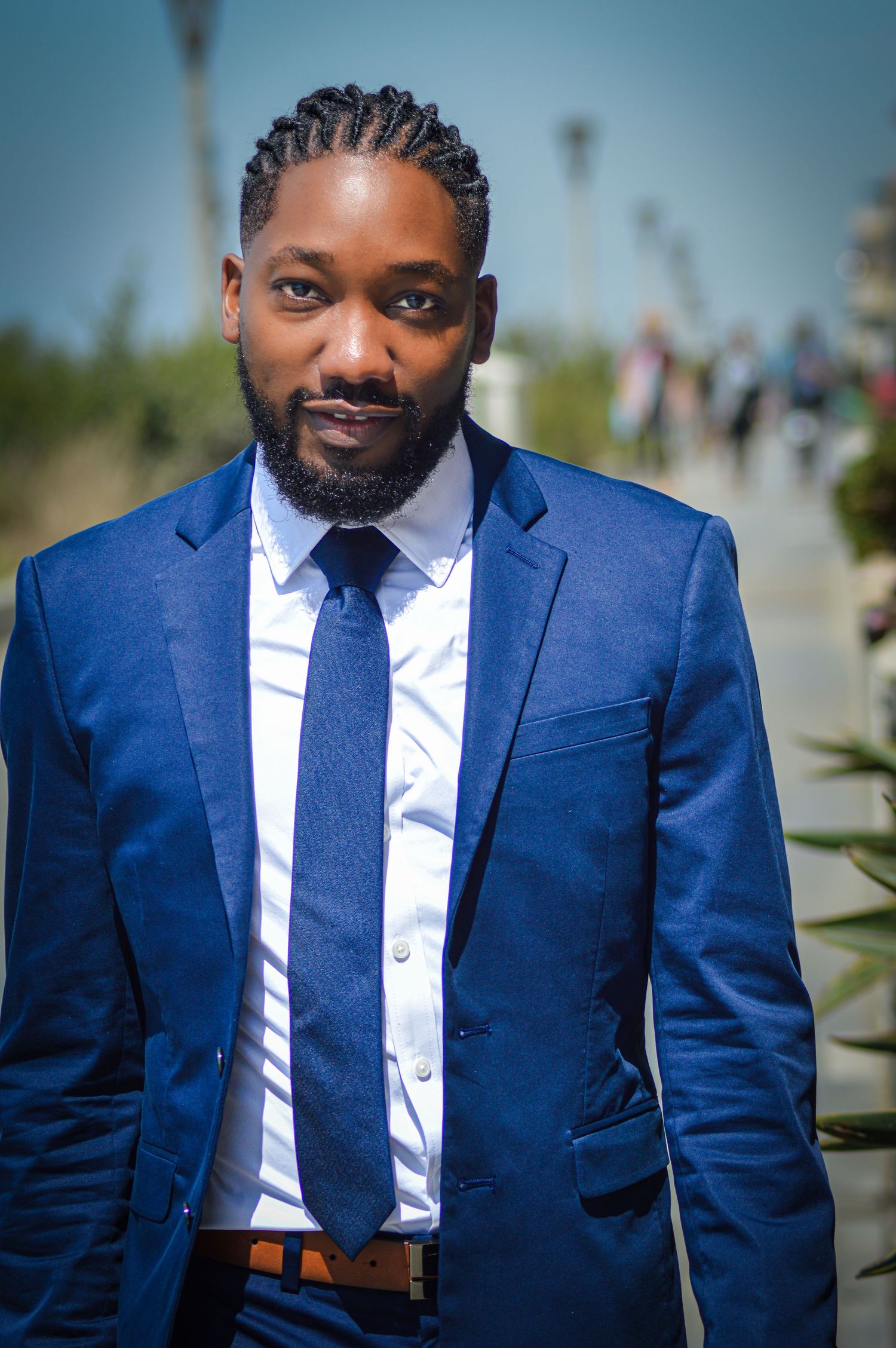 Professional portrait series showing a person in a tailored navy blue suit and white dress shirt against a blurred outdoor background.