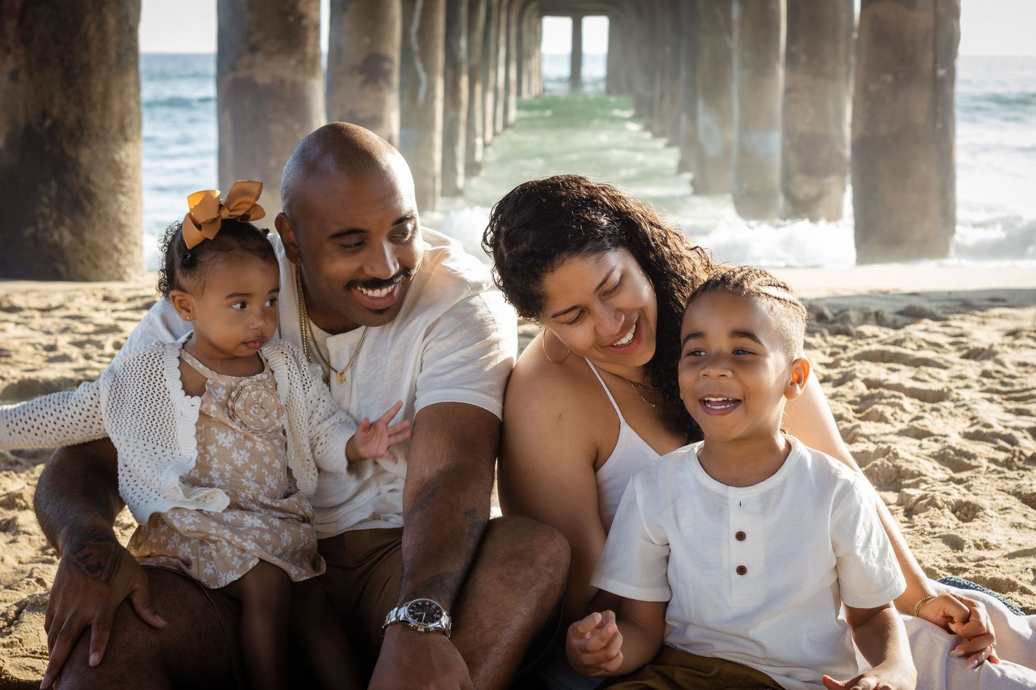 Family enjoying quality time together under a pier at the beach during sunset.