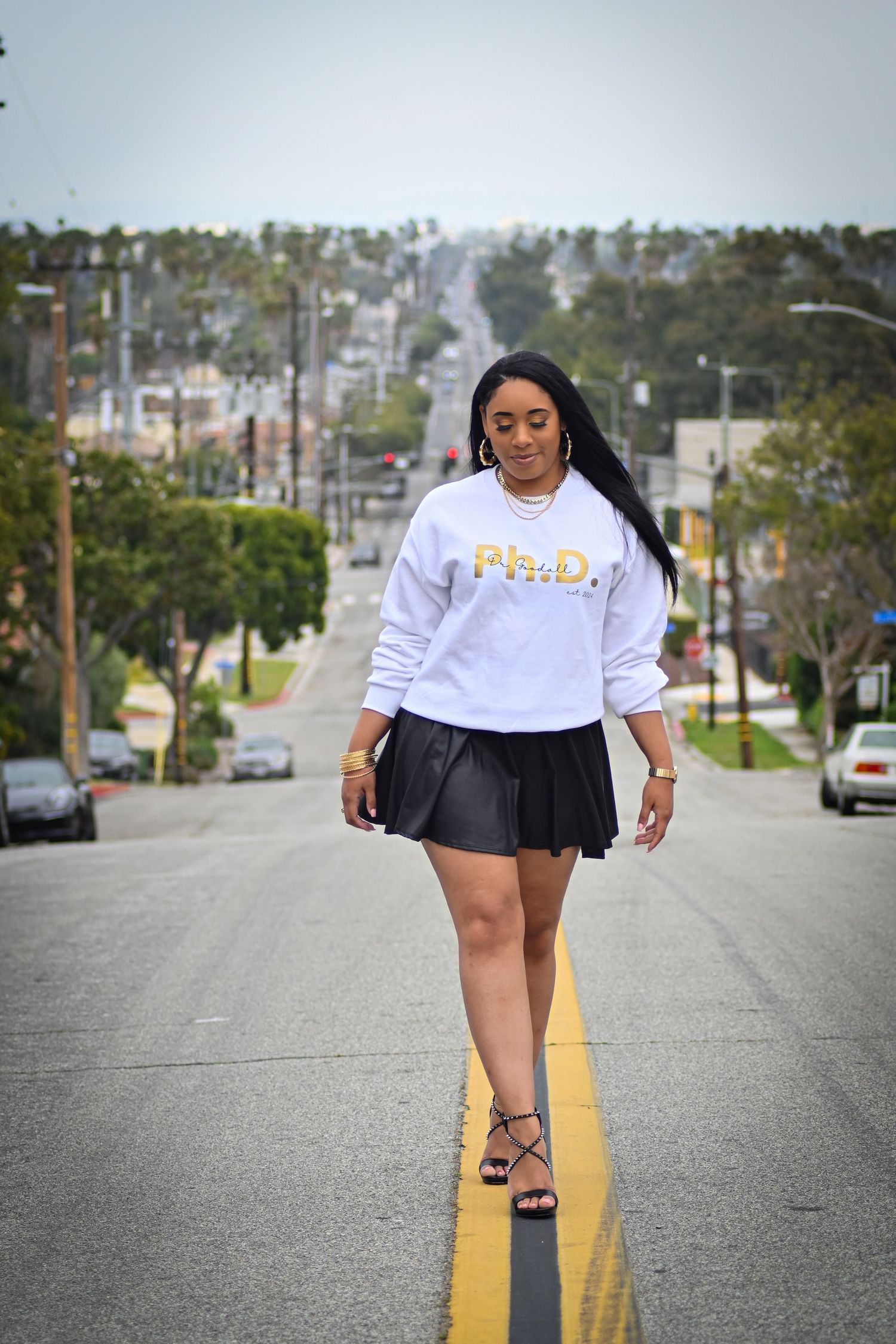 Walking down street in white sweatshirt and black skirt with yellow road line.