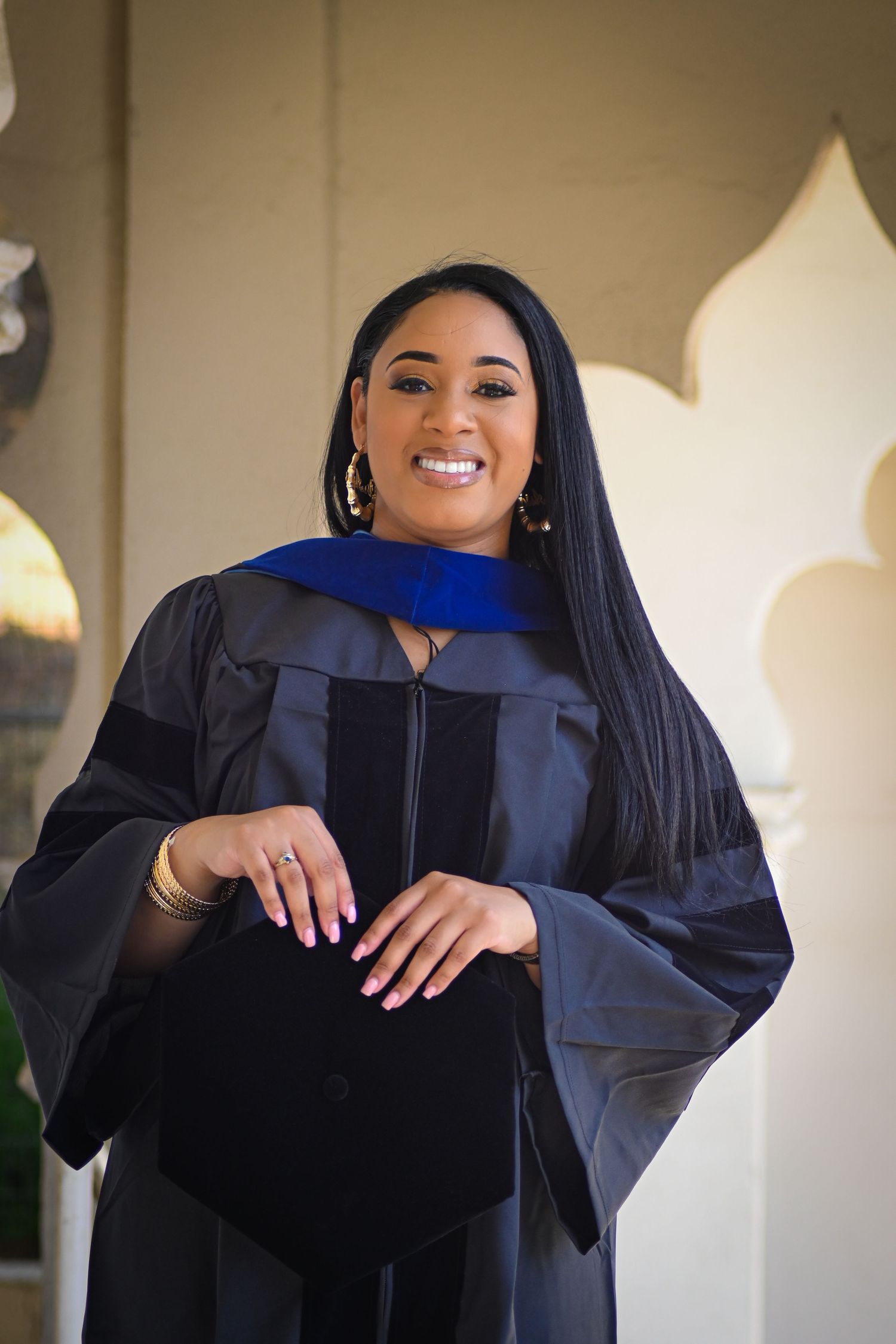 Graduate in black cap and gown smiling joyfully during graduation photoshoot.