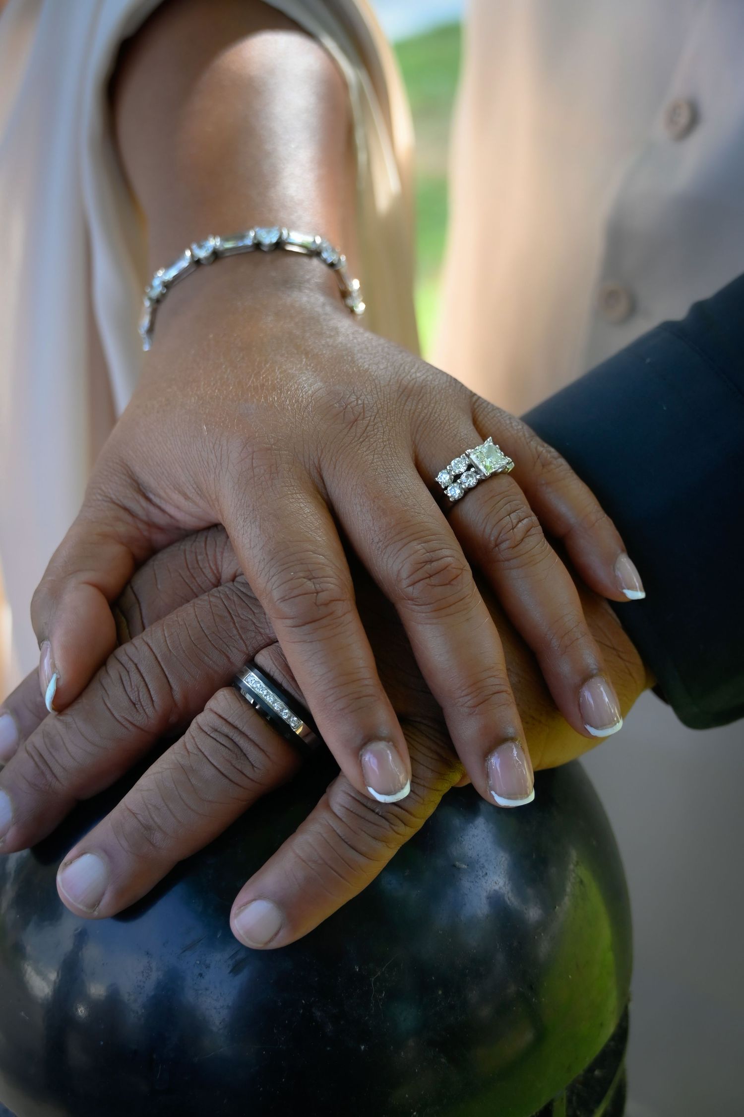 Newlywed couple displaying wedding rings and diamond bracelet with hands resting on a watermelon.