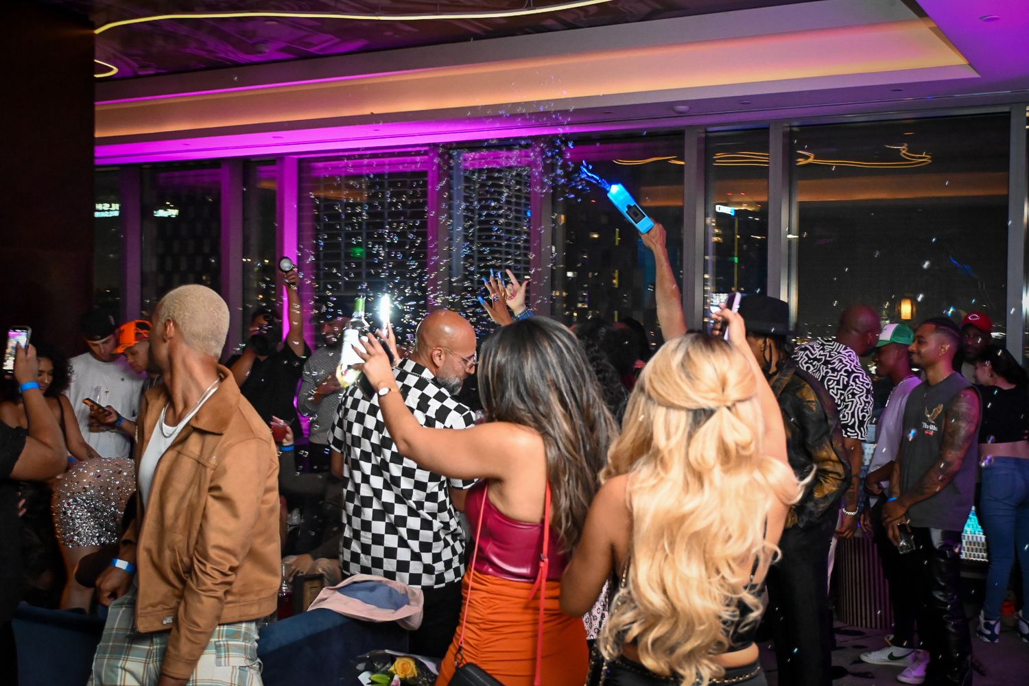Crowded nightclub scene with purple lighting and people dancing on a busy dance floor.