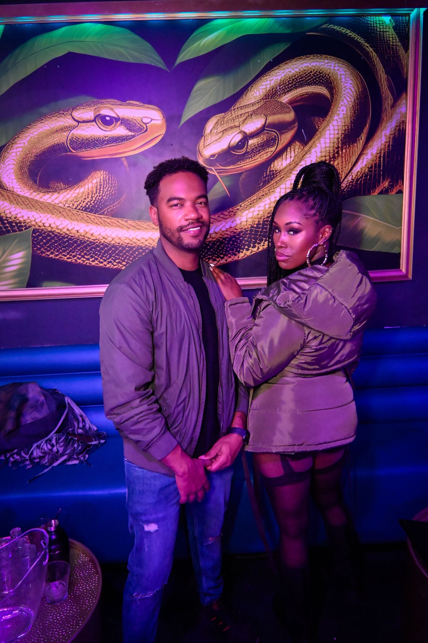 A couple dancing together in a nightclub with colorful purple and blue lighting and decorative wall designs.
