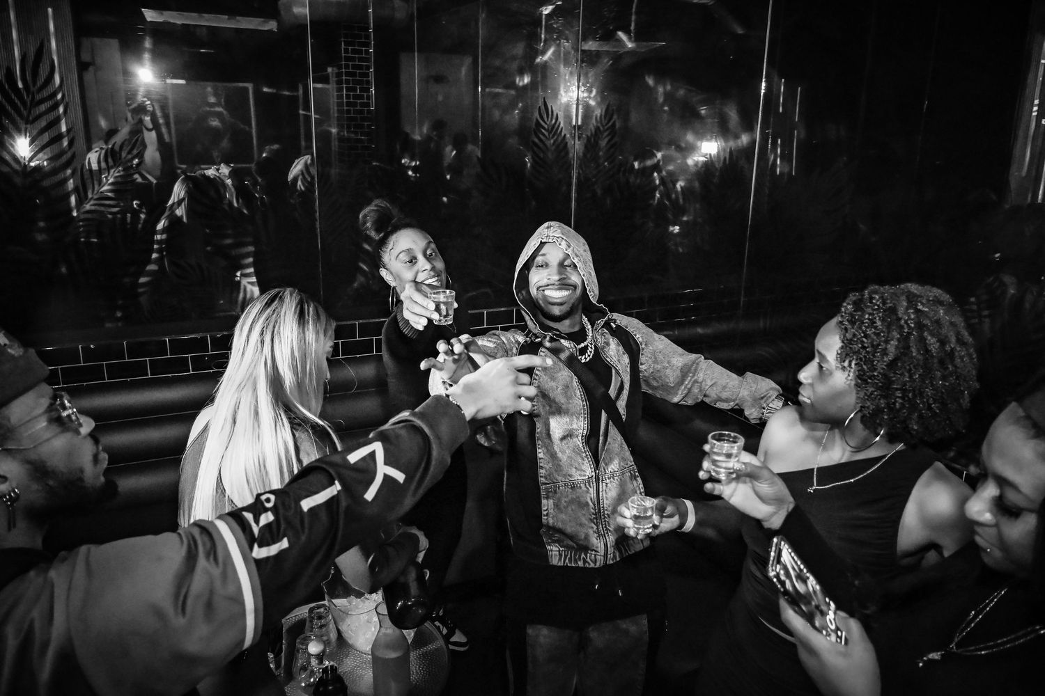 Group of people enjoying a lively nightclub atmosphere with drinks and dancing.