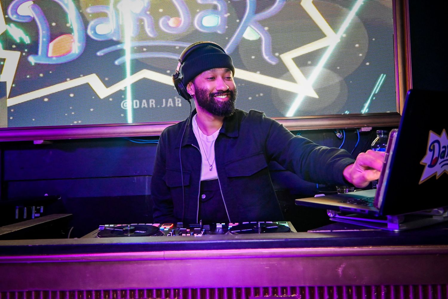 DJ performs at a nightclub with purple lighting and electronic equipment visible in a series of connected images.