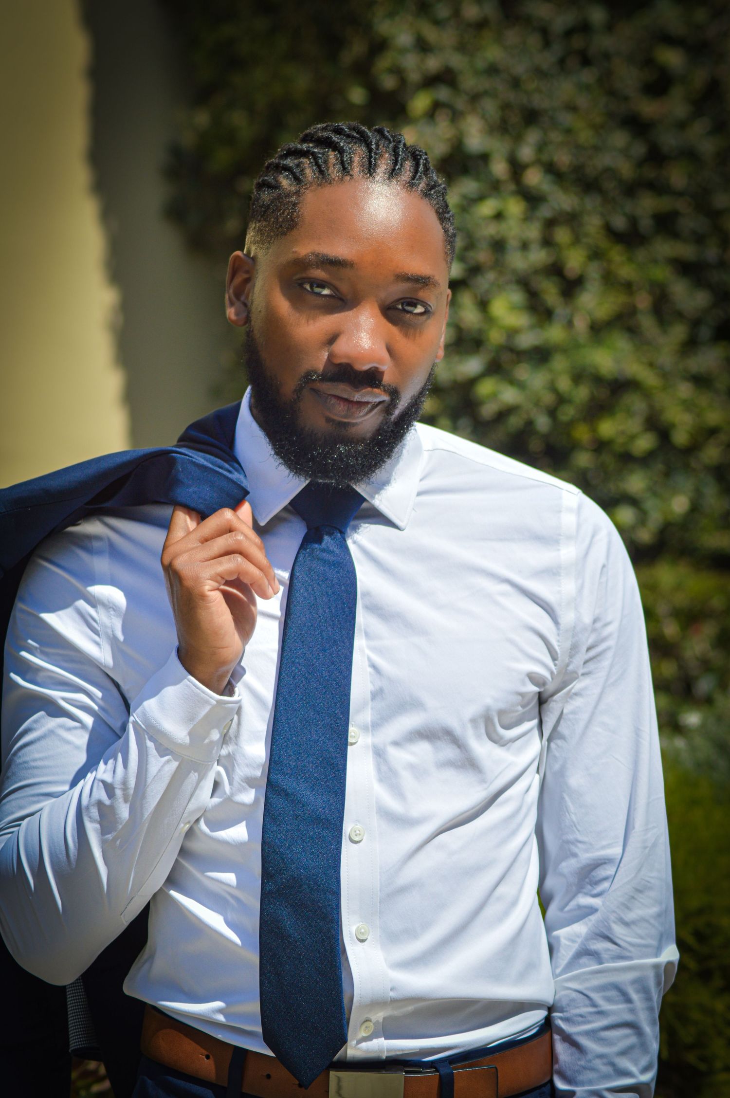 Professional portrait series showing a person in a crisp white dress shirt and navy blue tie against a natural backdrop.