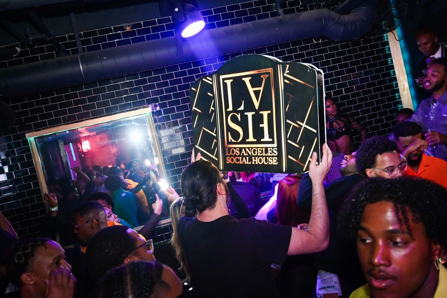 A nightclub scene with purple and red lighting illuminates people dancing and socializing at a crowded venue.