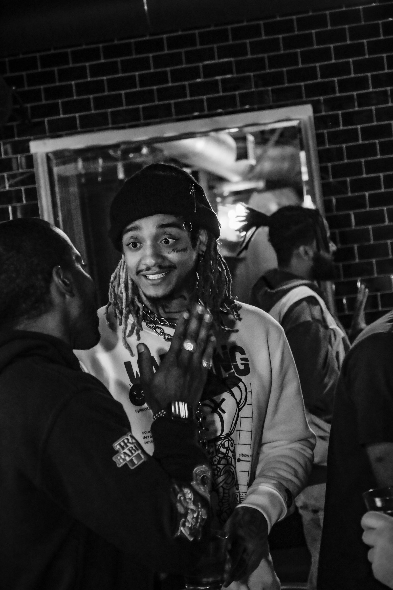 Black and white photo sequence showing a person with dreadlocks smiling and gesturing at a nighttime event.