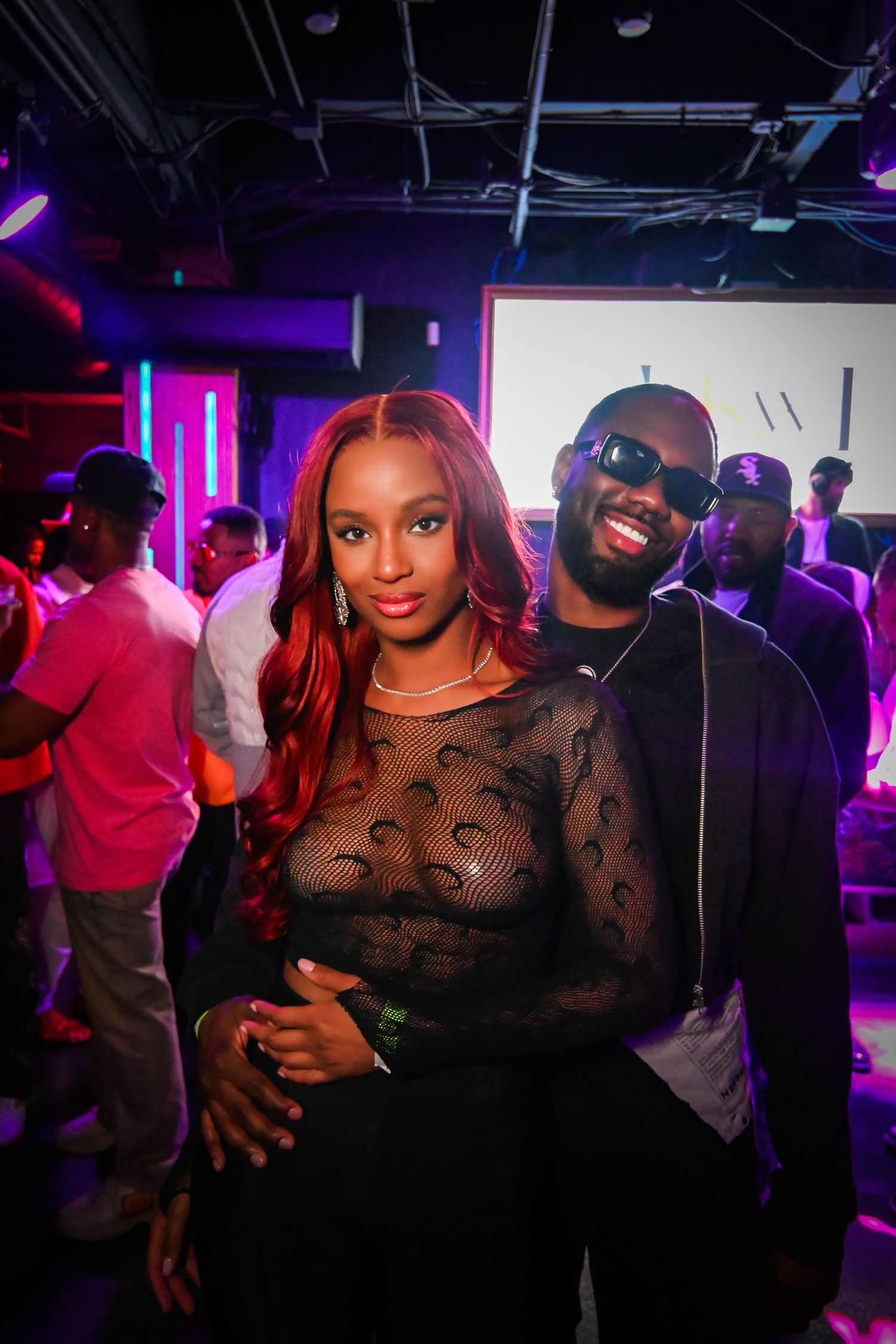 People dancing and socializing at a nightclub with purple lighting and dark atmosphere.