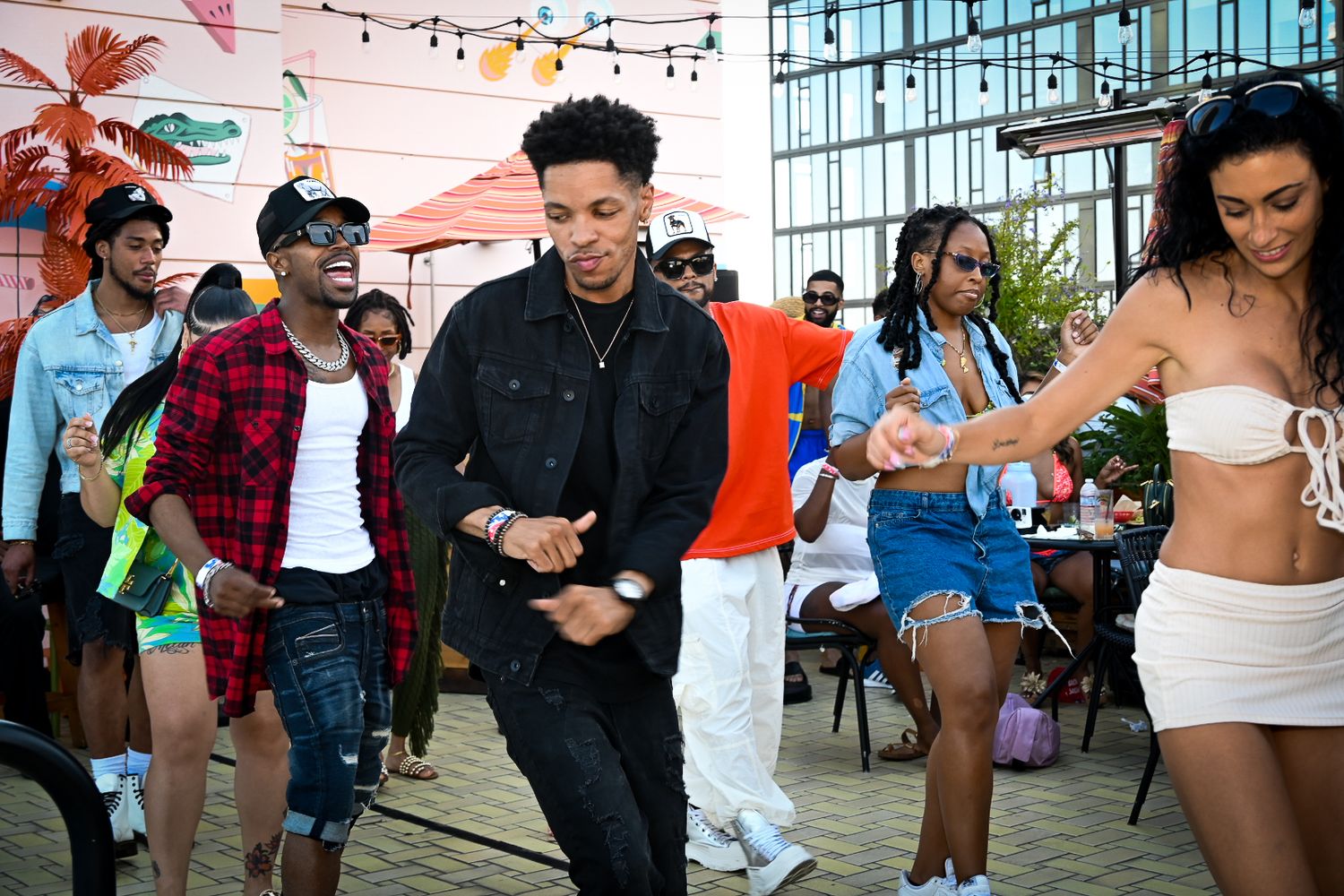 People dancing together at an outdoor party with string lights and fall decorations.