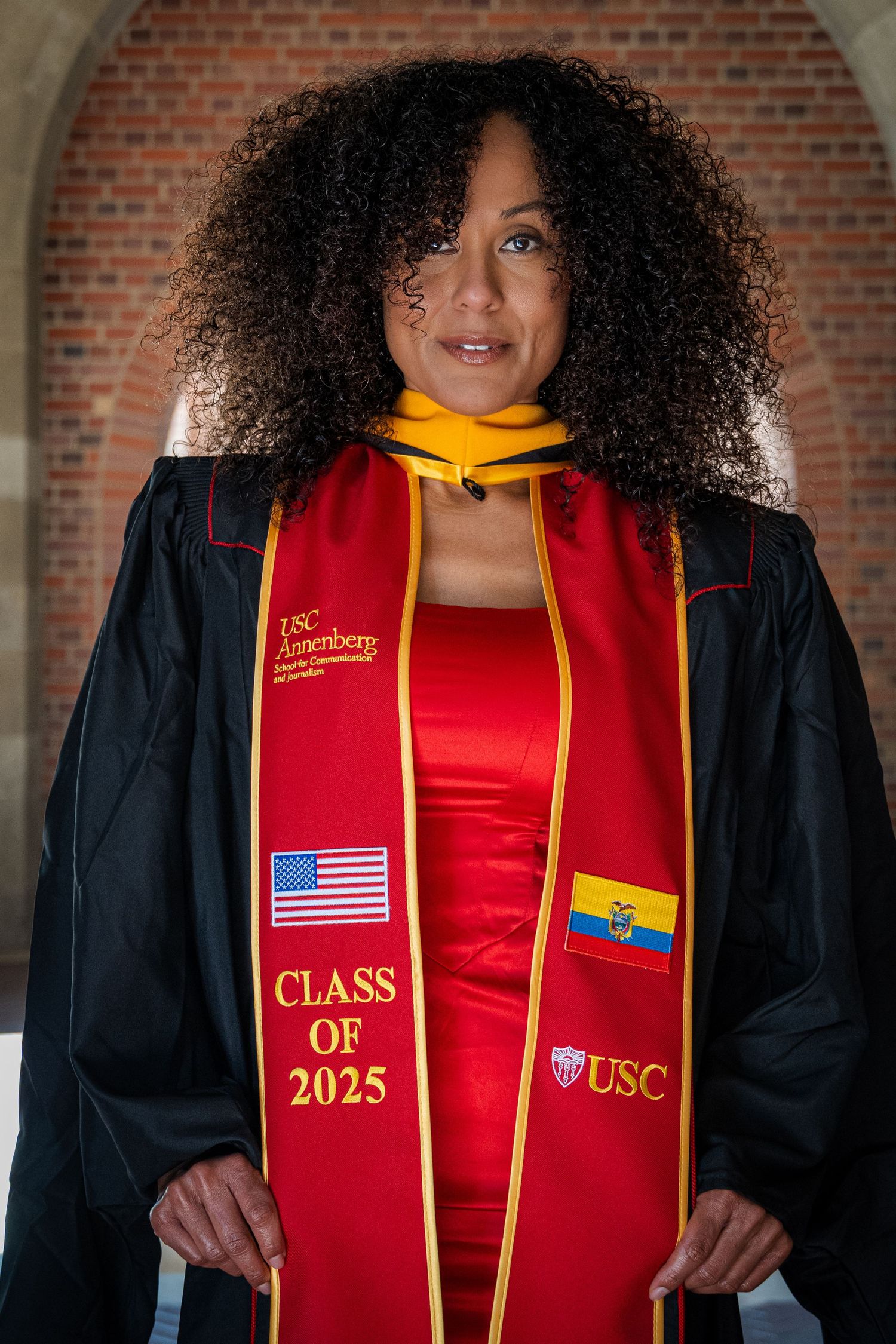 USC graduate wearing Class of 2025 stole with American and Ecuadorian flags poses in academic regalia.
