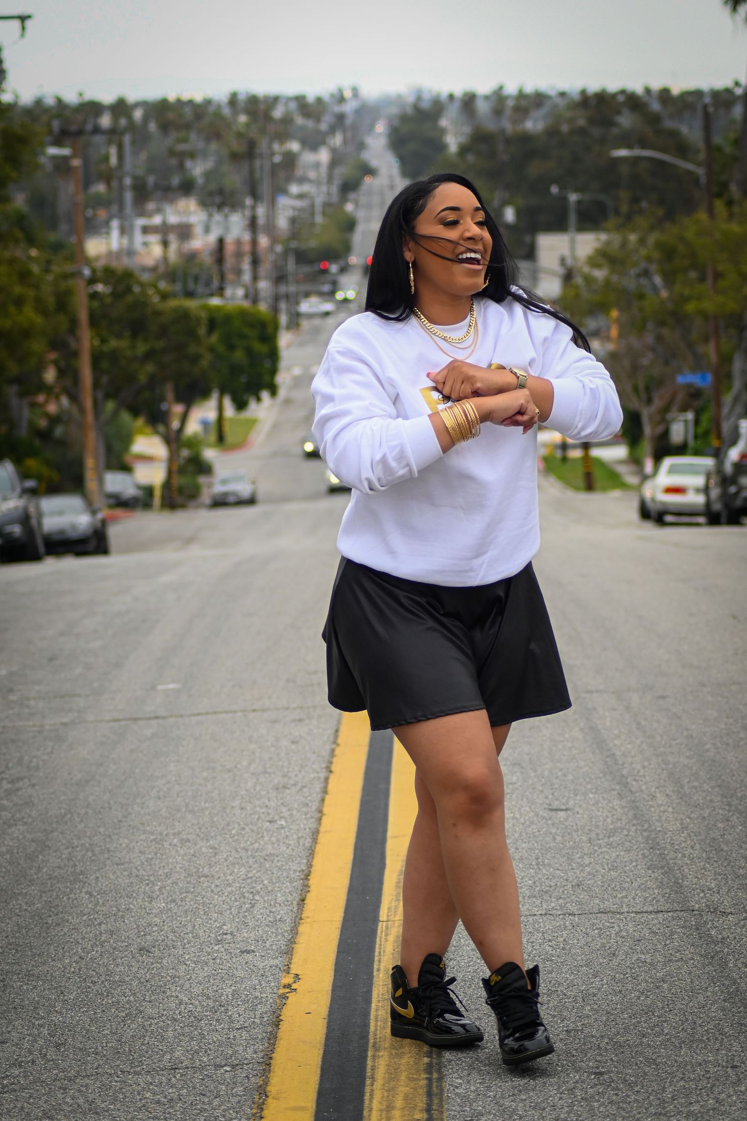 Dynamic street fashion photo showing movement in a white sweatshirt and black skirt.