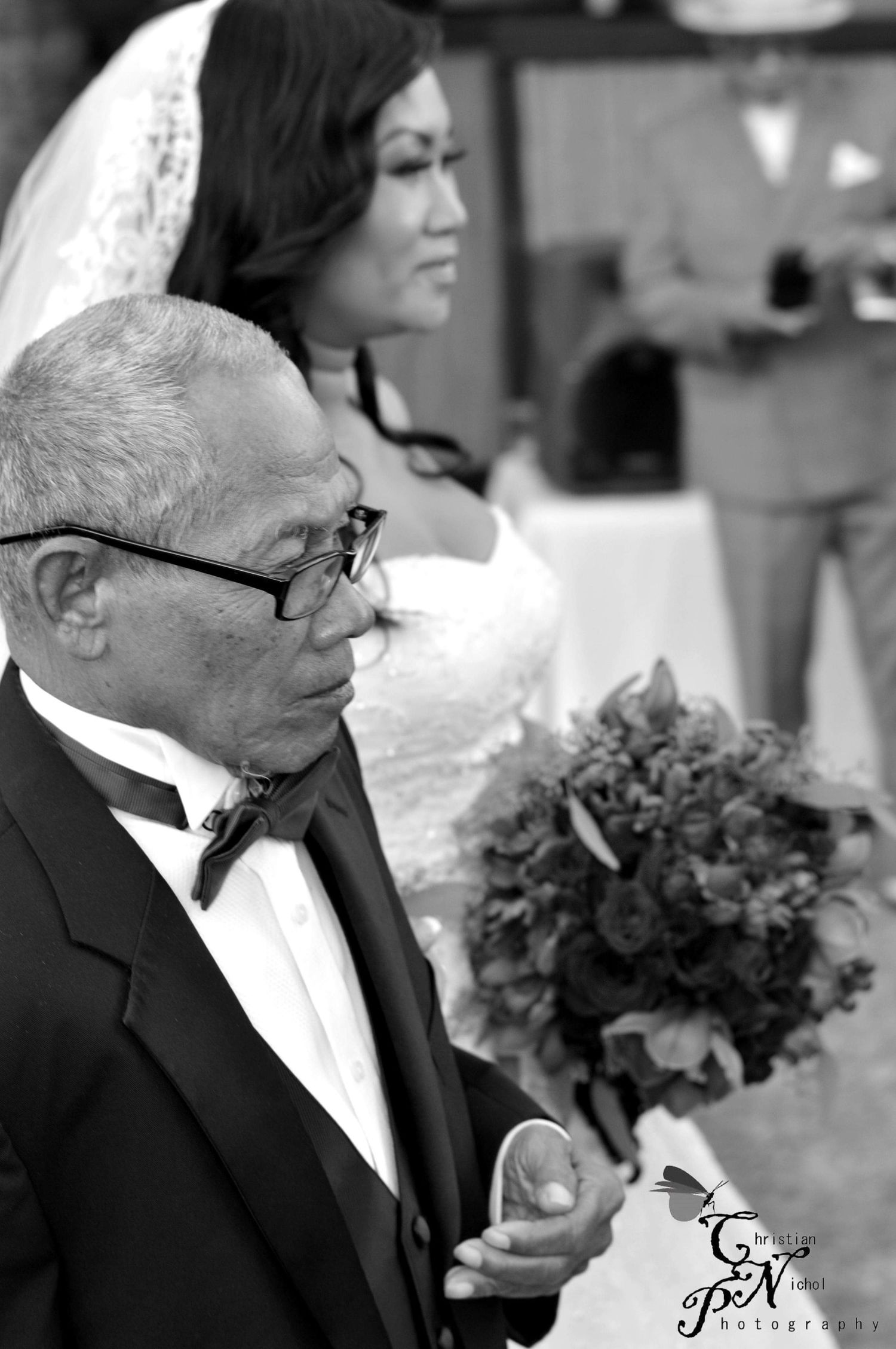 Black and white photo of a father walking his bride daughter down the aisle, holding a bouquet at a wedding.