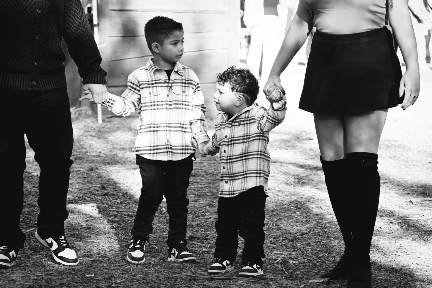A black and white photo showing legs and feet of adults and children walking together outdoors.