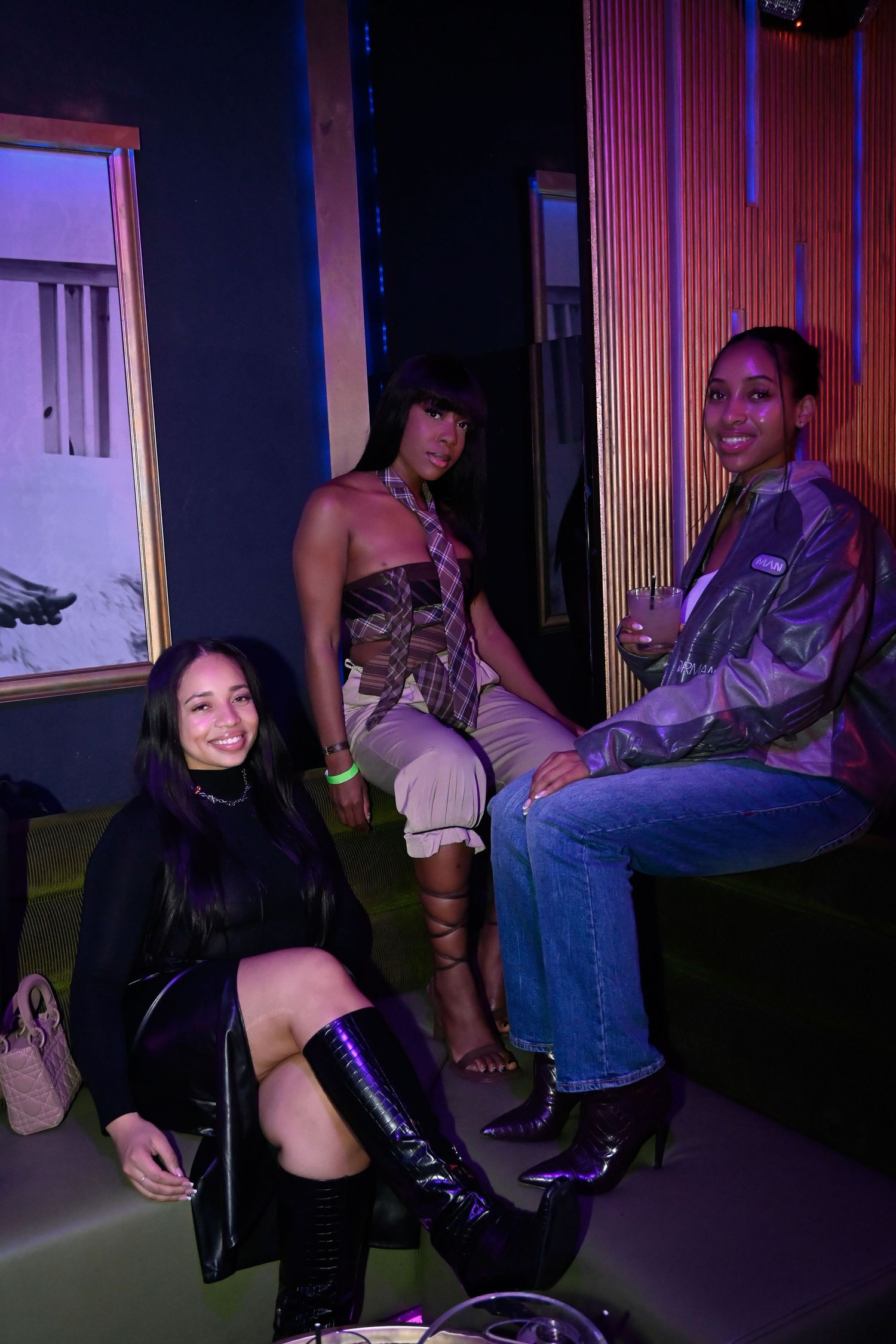 A group of people dancing and socializing in a dimly lit room with purple lighting.