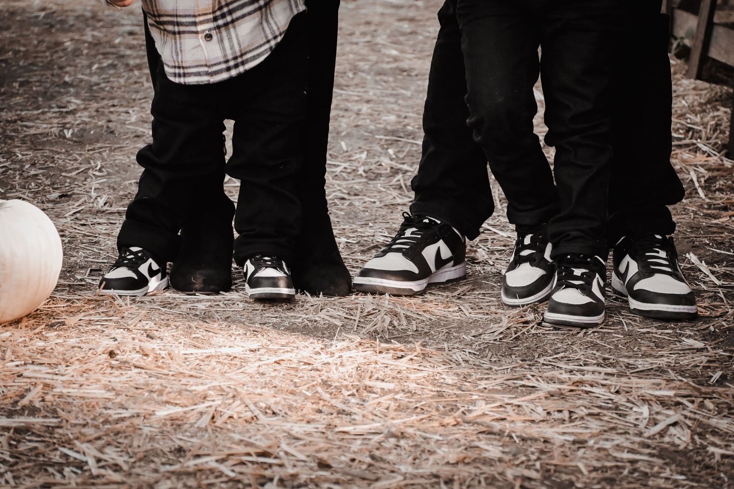 A row of people's feet wearing various sneakers and shoes standing in line on a textured ground surface.