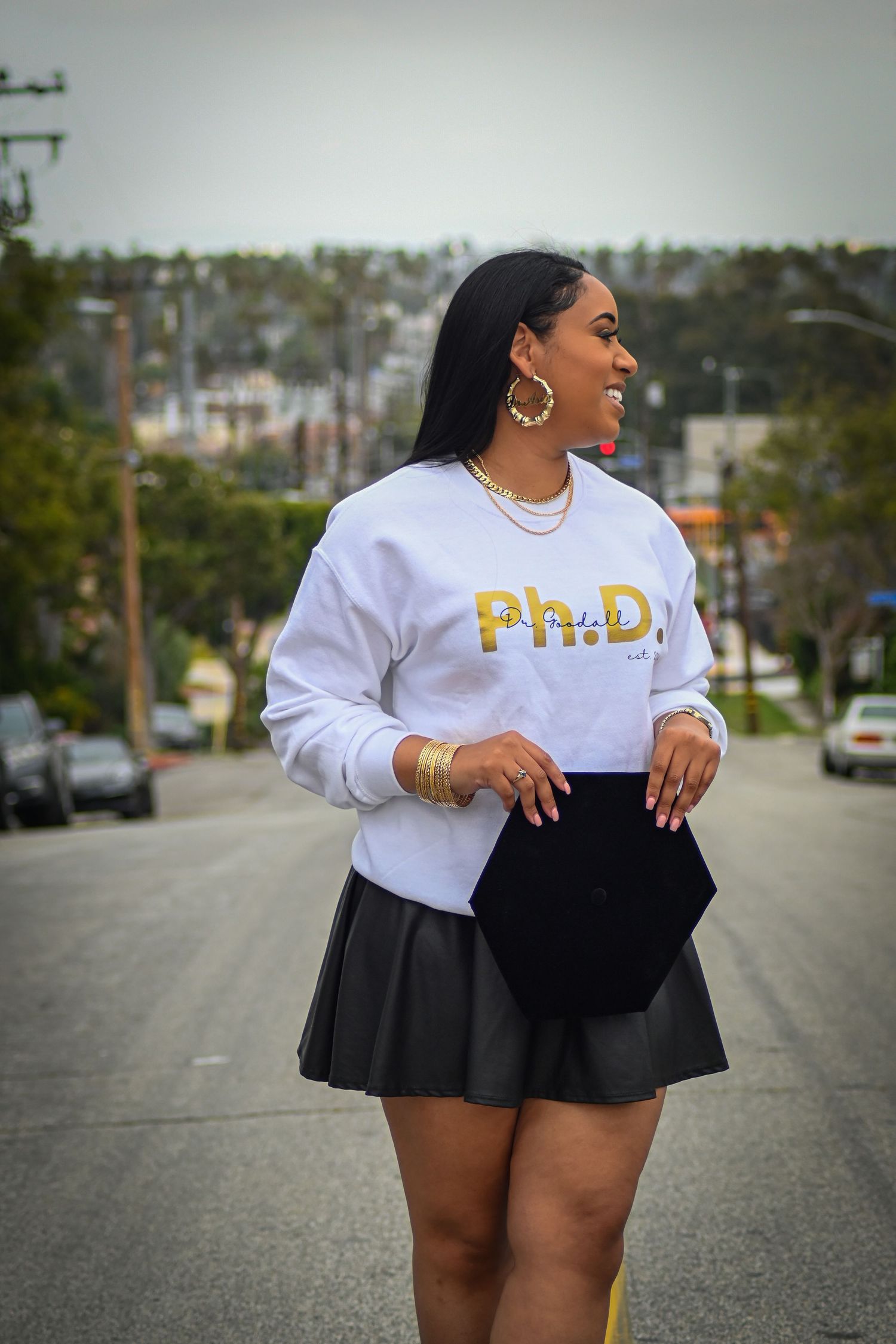 Street fashion photo in a white Ph.D. sweatshirt and black pleated skirt.