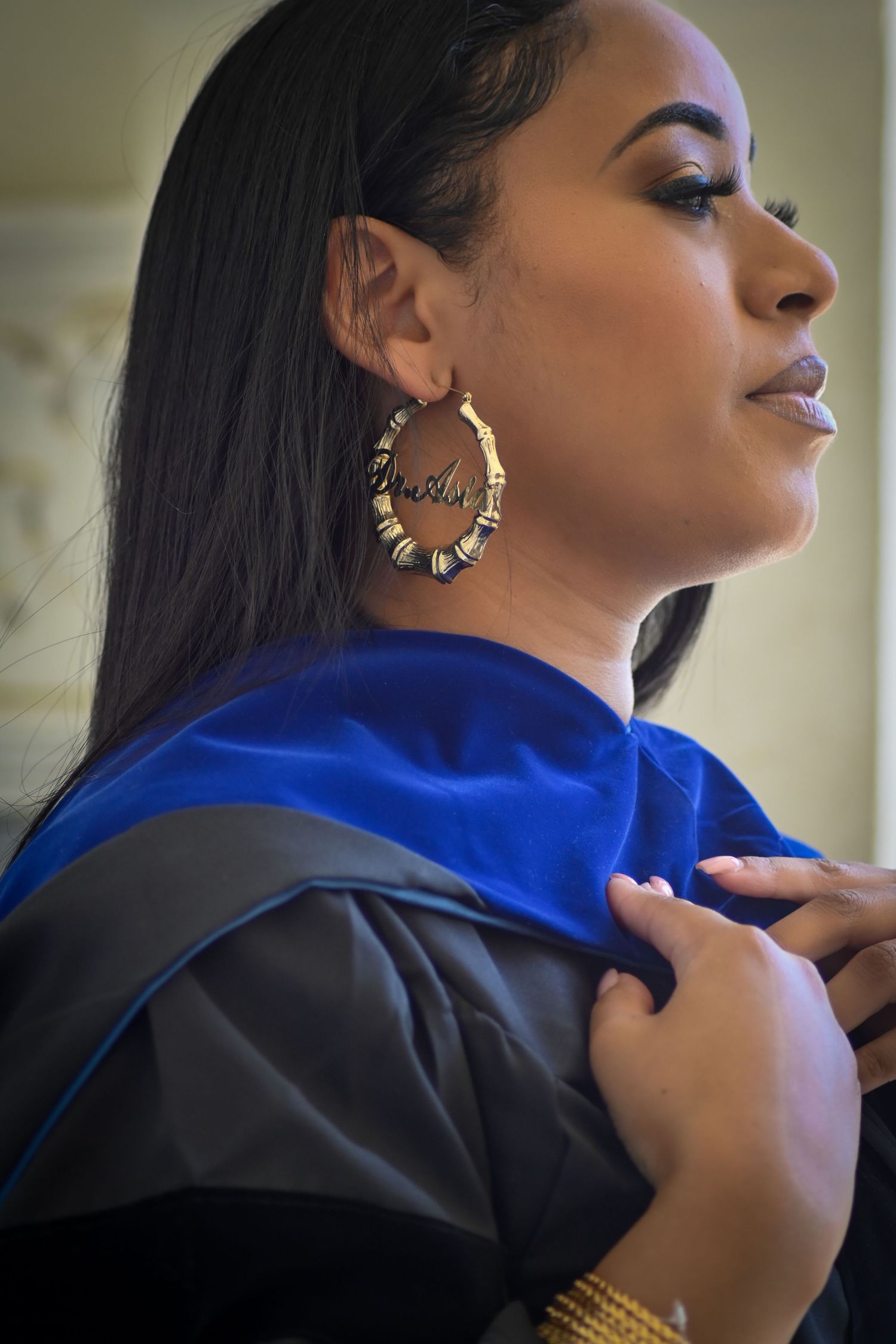 Close-up profile view of graduate wearing decorative gold earrings and blue graduation stole.