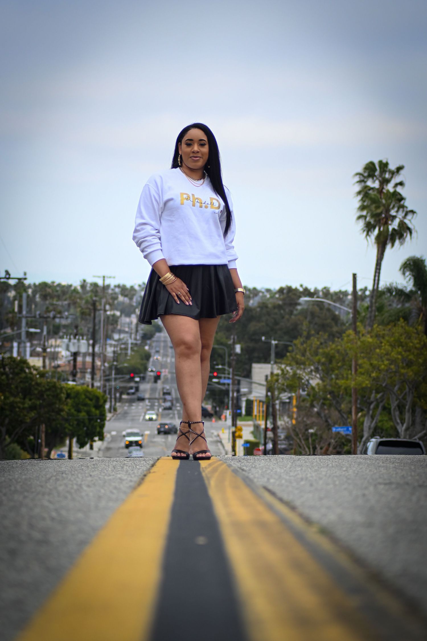Creative perspective shot standing on yellow road lines wearing casual white and black outfit.