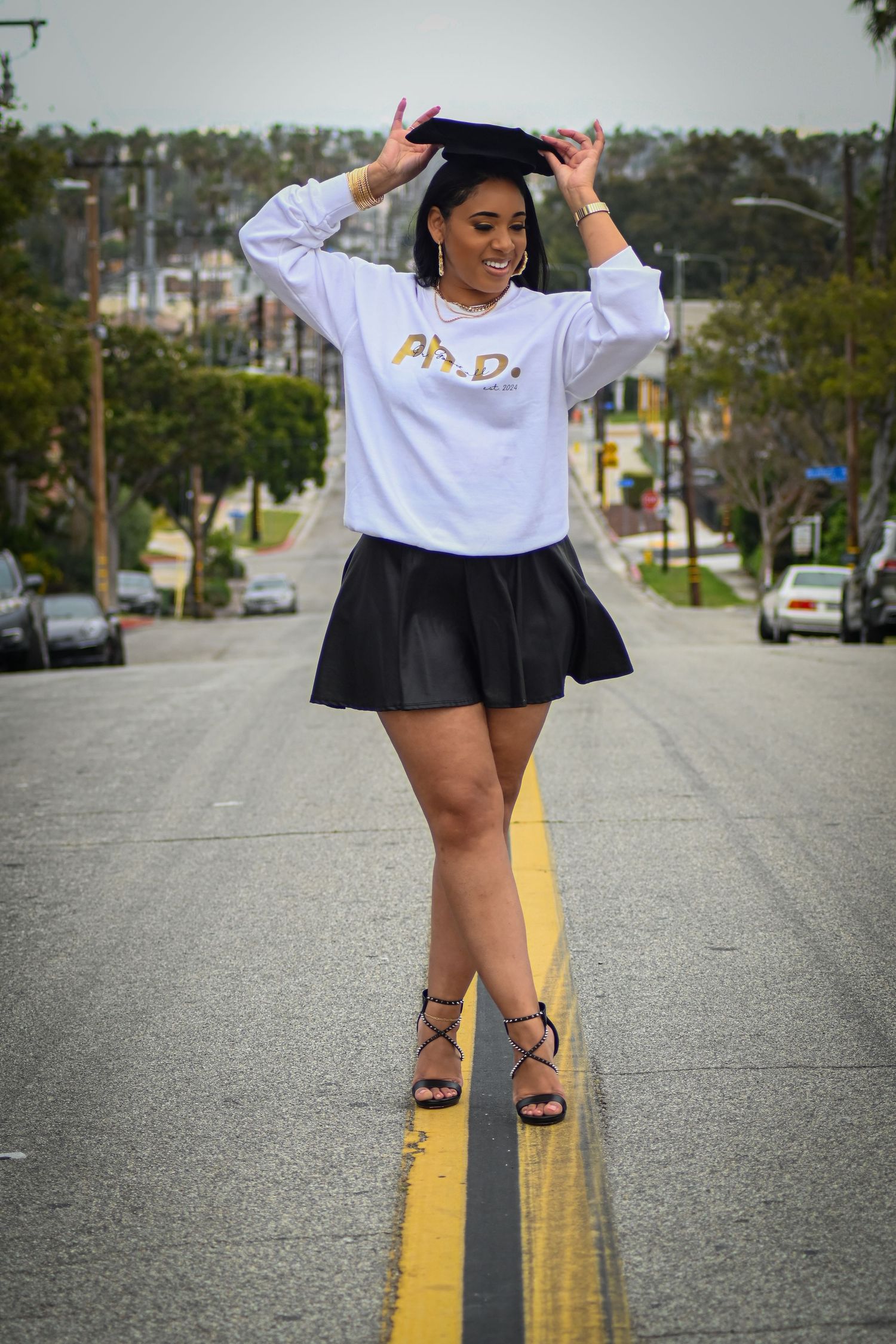Playful street photography featuring a white Ph.D. sweatshirt and black skirt outfit.