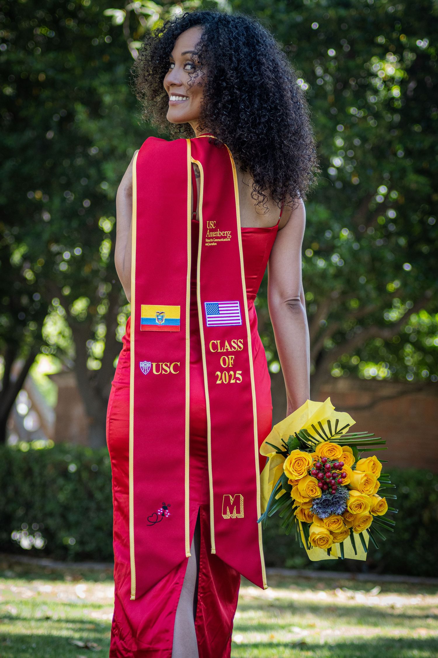Graduate in red dress with USC Class of 2015 stole holding yellow flower bouquet.