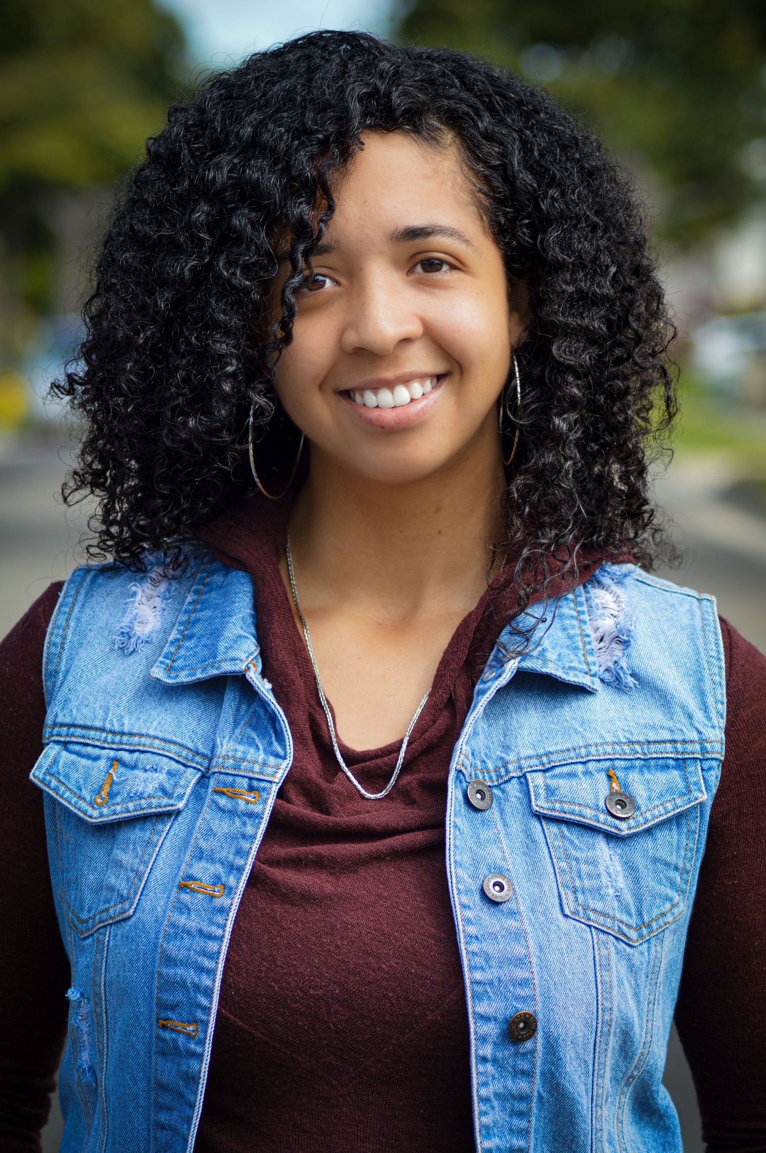A series of four portrait photos showing someone with curly hair wearing a burgundy top and denim jacket.