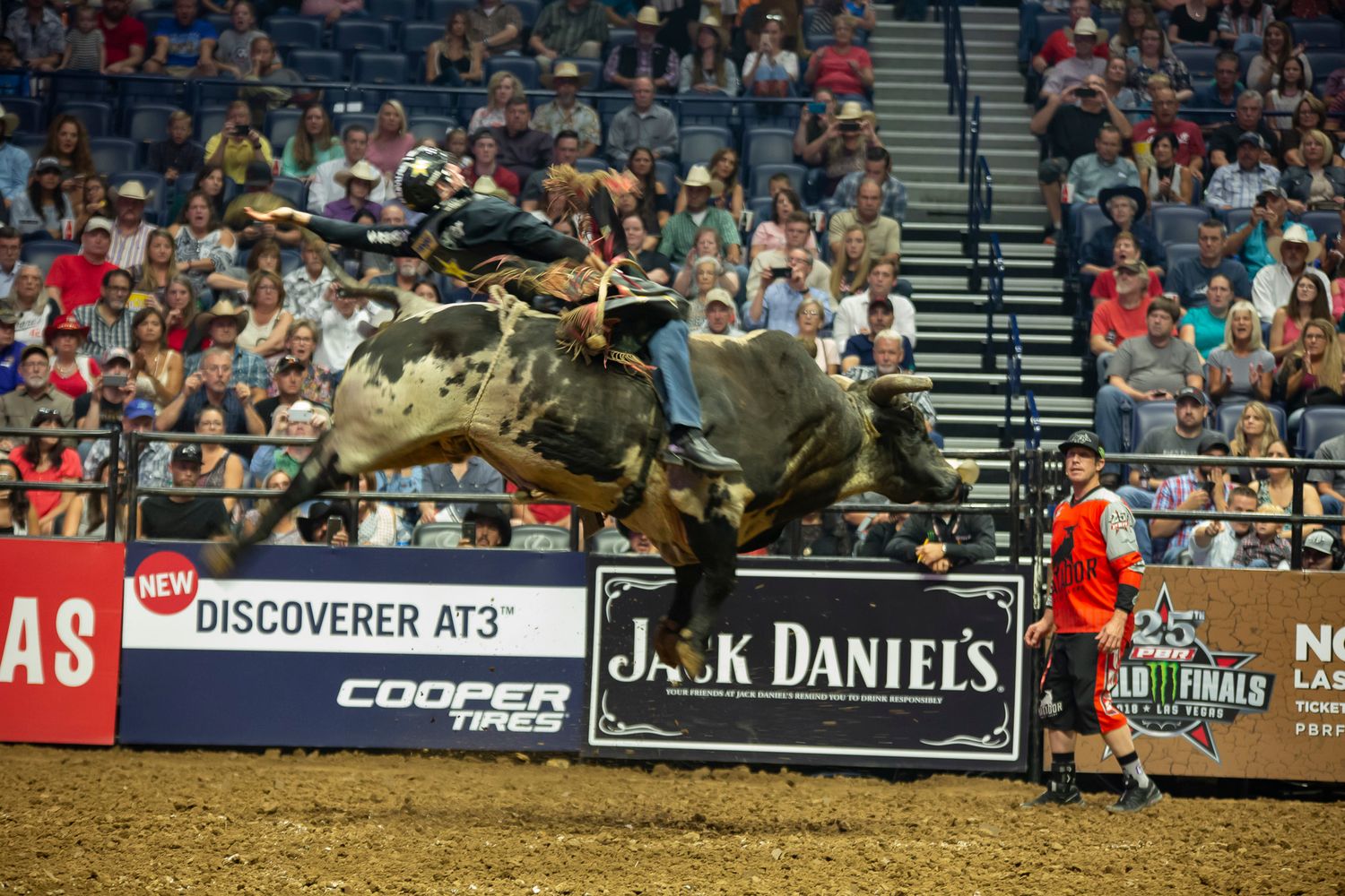Packed arena crowd watches intense bull riding action at professional rodeo event. PBR World Finals Las Vegas