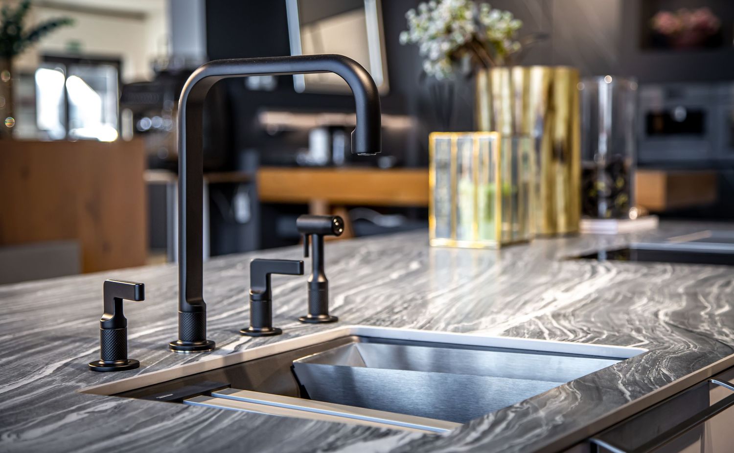 Luxury kitchen featuring a matte black faucet with side sprayer on a dark marble countertop with undermount sink.