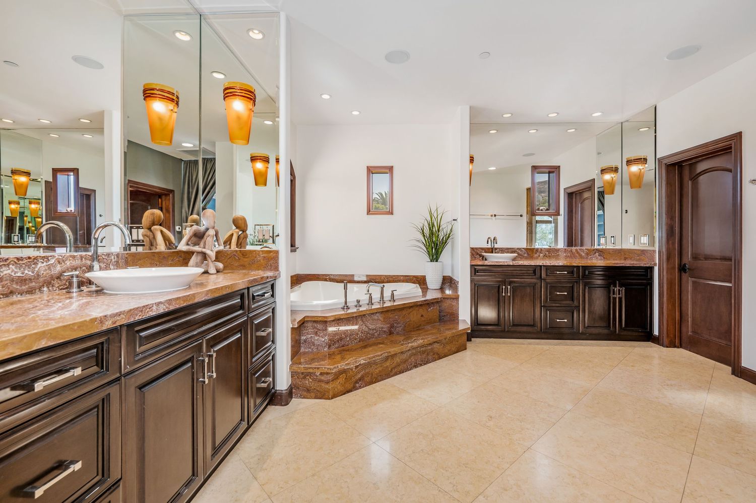 Spacious master bathroom featuring dual vanities, granite countertops, soaking tub, and warm pendant lighting.