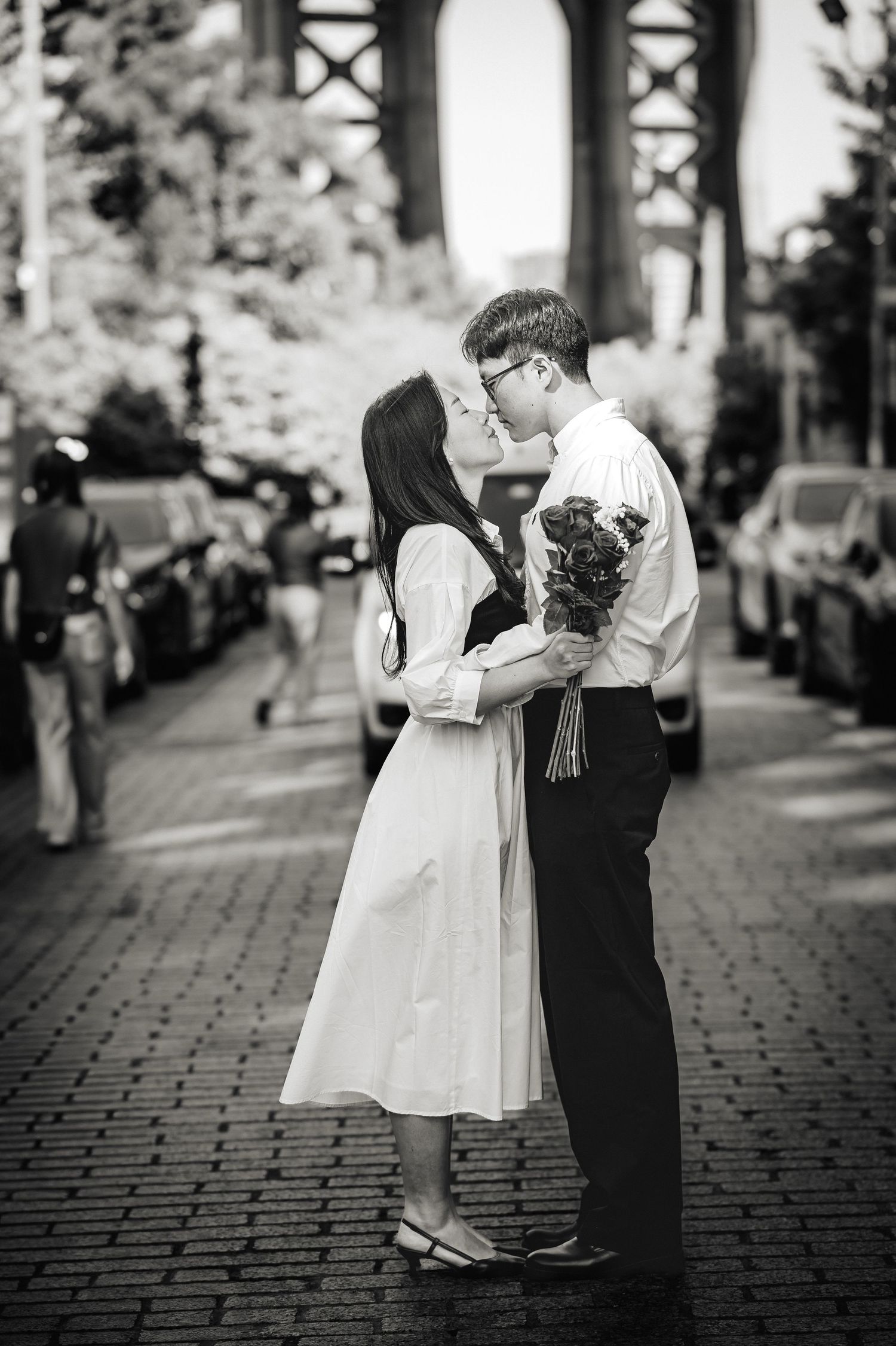 Romantic couple photos taken on a cobblestone path with urban architecture in the background.