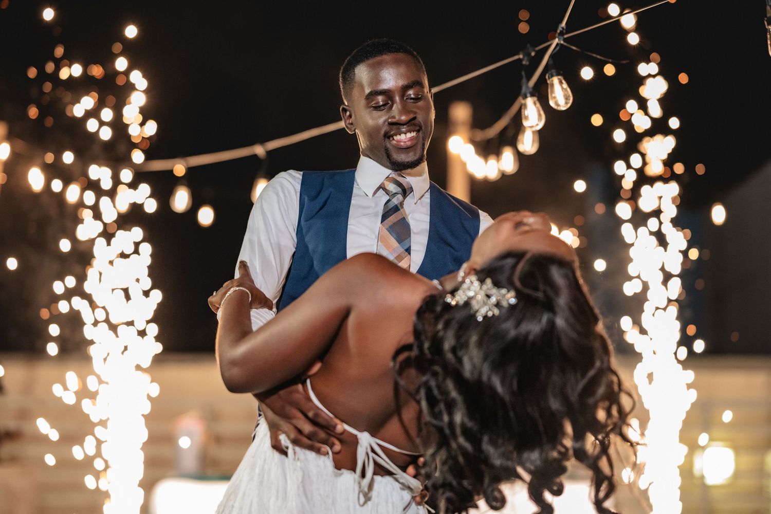 Romantic dance scene with sparklers and string lights creating magical evening atmosphere.