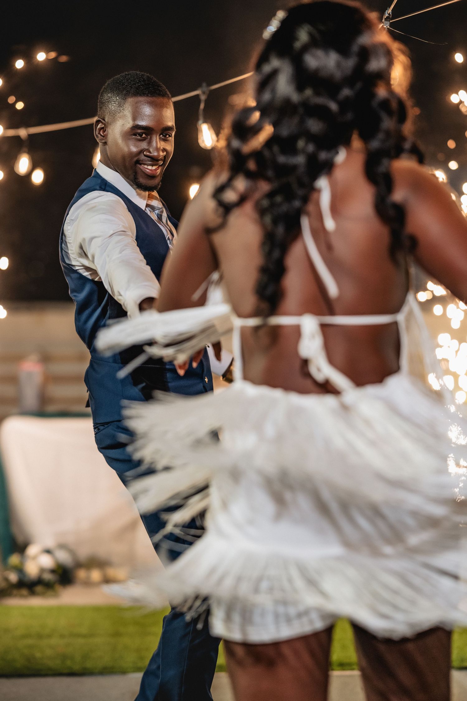 Wedding couple dances together during a sparkler-lit evening reception celebration.