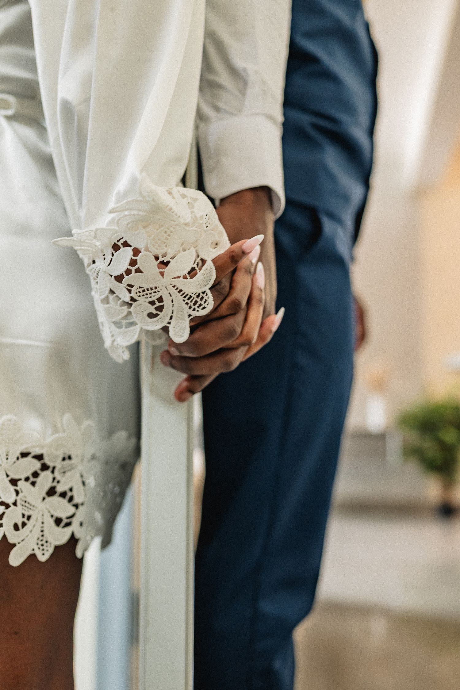 Close-up details of white lace dress hem and formal attire during a wedding ceremony.