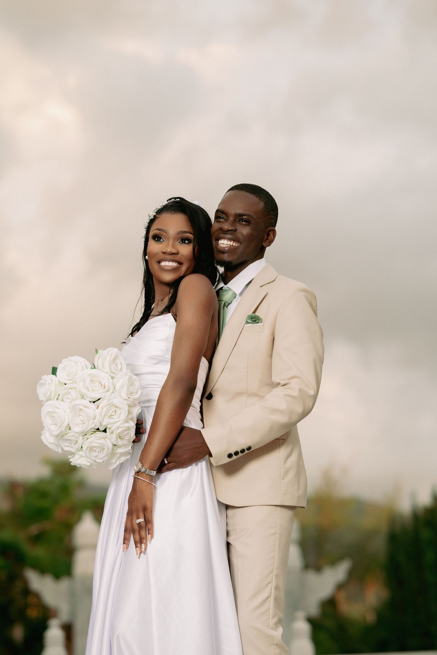 Happy couple in wedding attire embrace and smile during outdoor photo session.