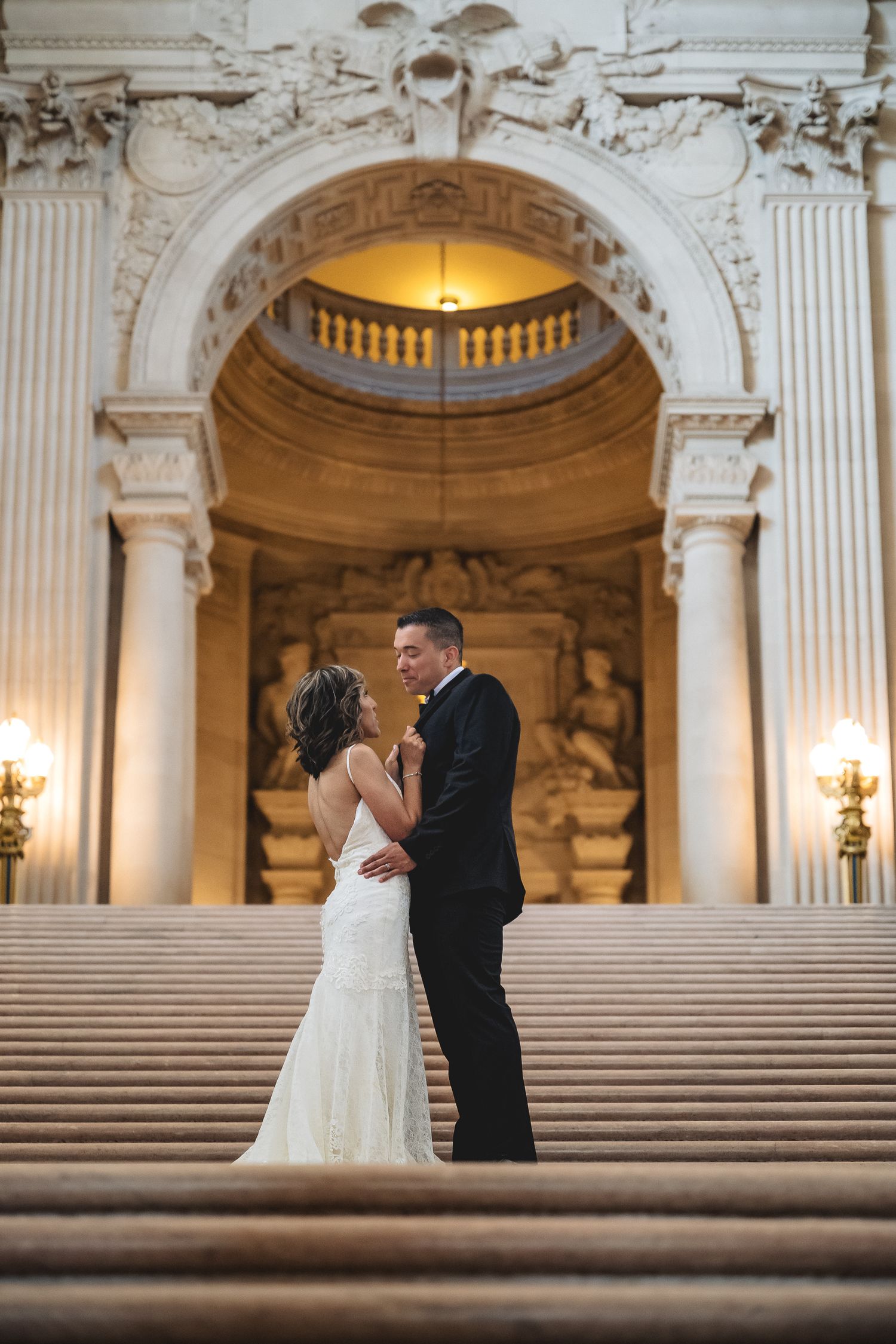 Bride and groom share a romantic moment on grand staircase at San Francisco City Hall wedding ceremony.
