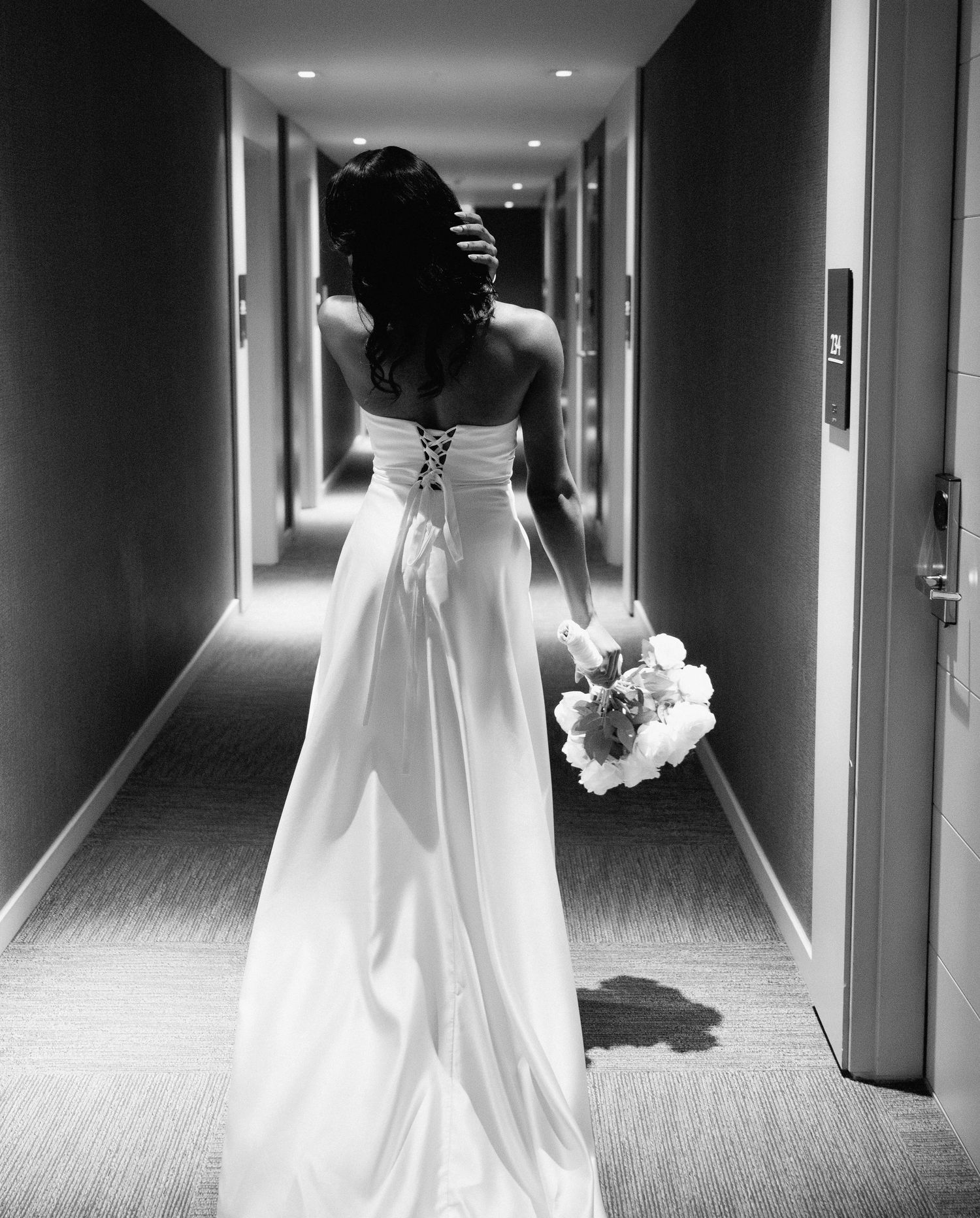 Black and white hallway shots showing the back details of an elegant wedding gown.