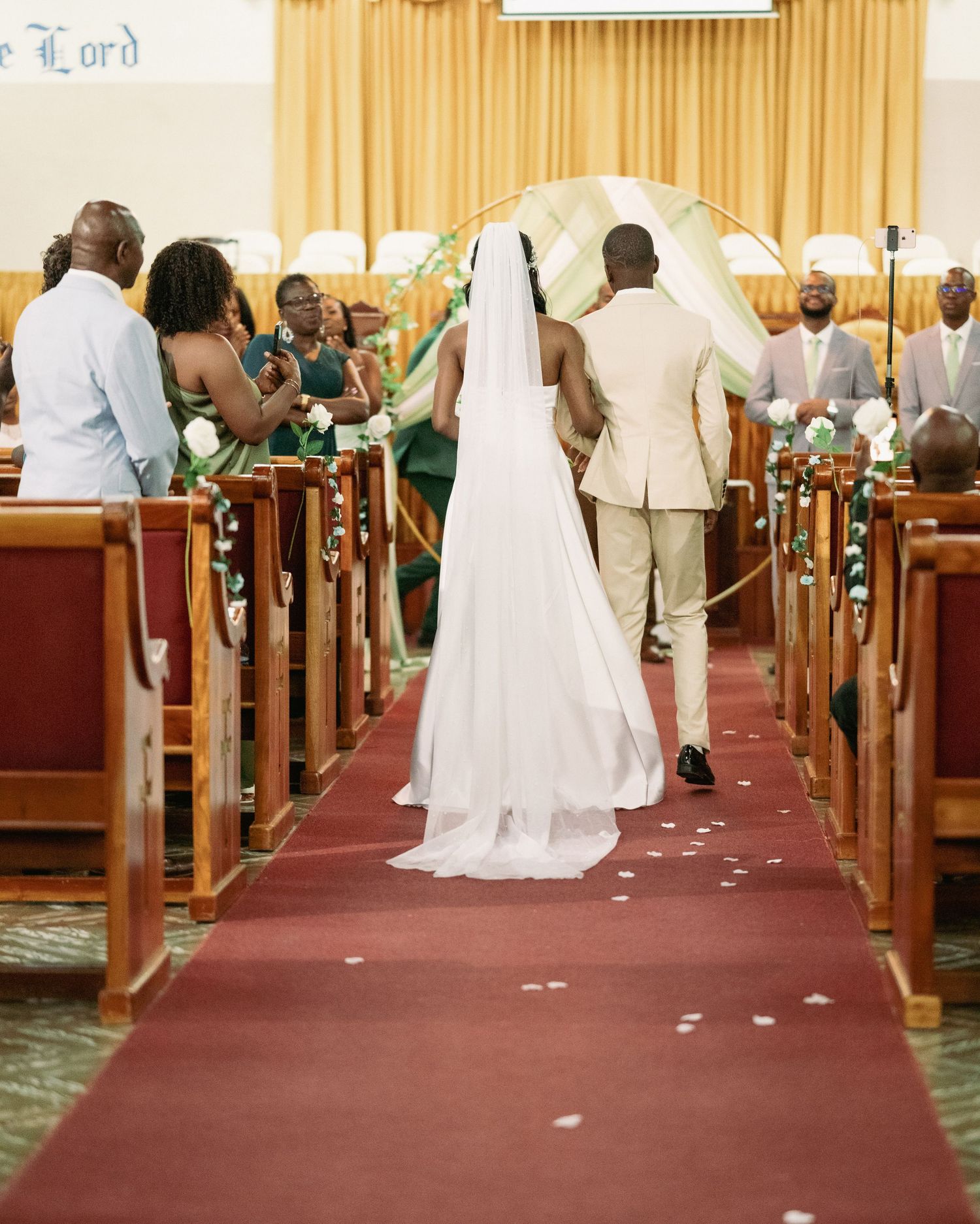 Bride and groom walking down the red carpet aisle of a church during their wedding ceremony.