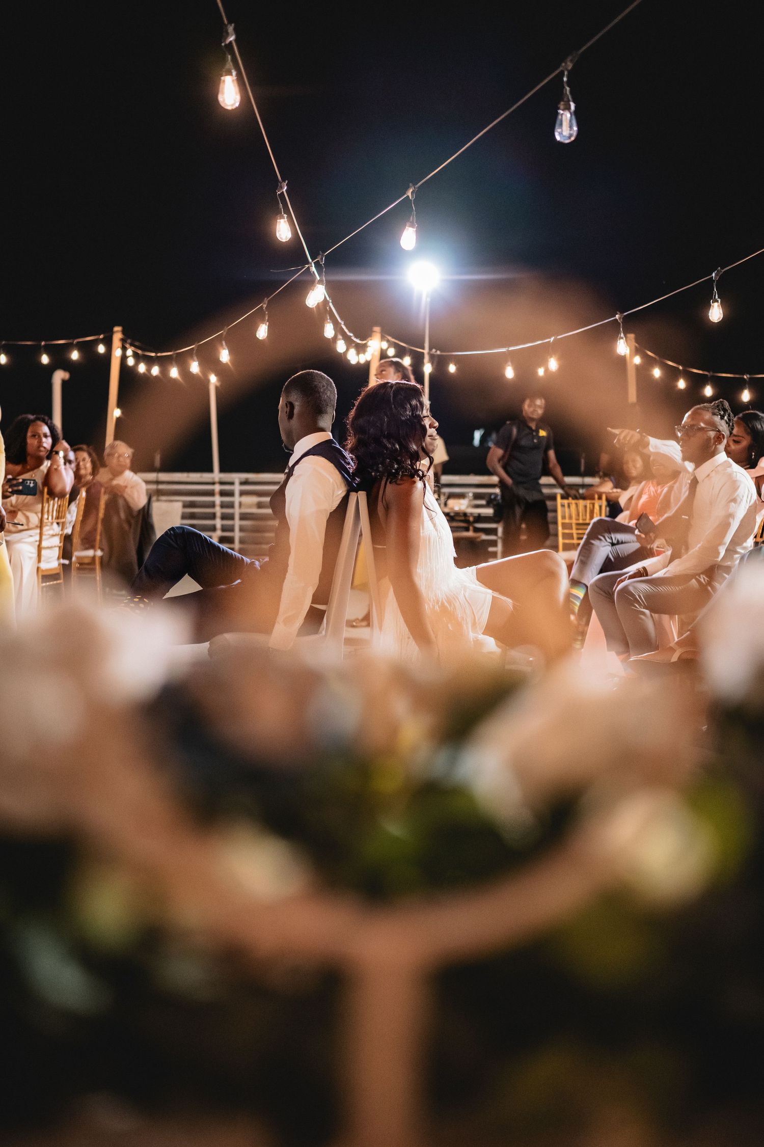String lights illuminate an outdoor evening celebration with dancing silhouettes creating a romantic ambiance.