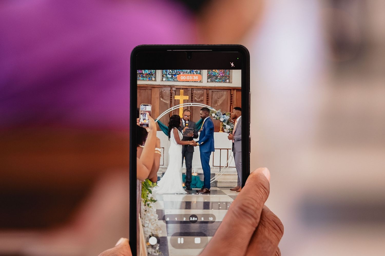 Someone holding a smartphone displaying wedding photos during a celebration.