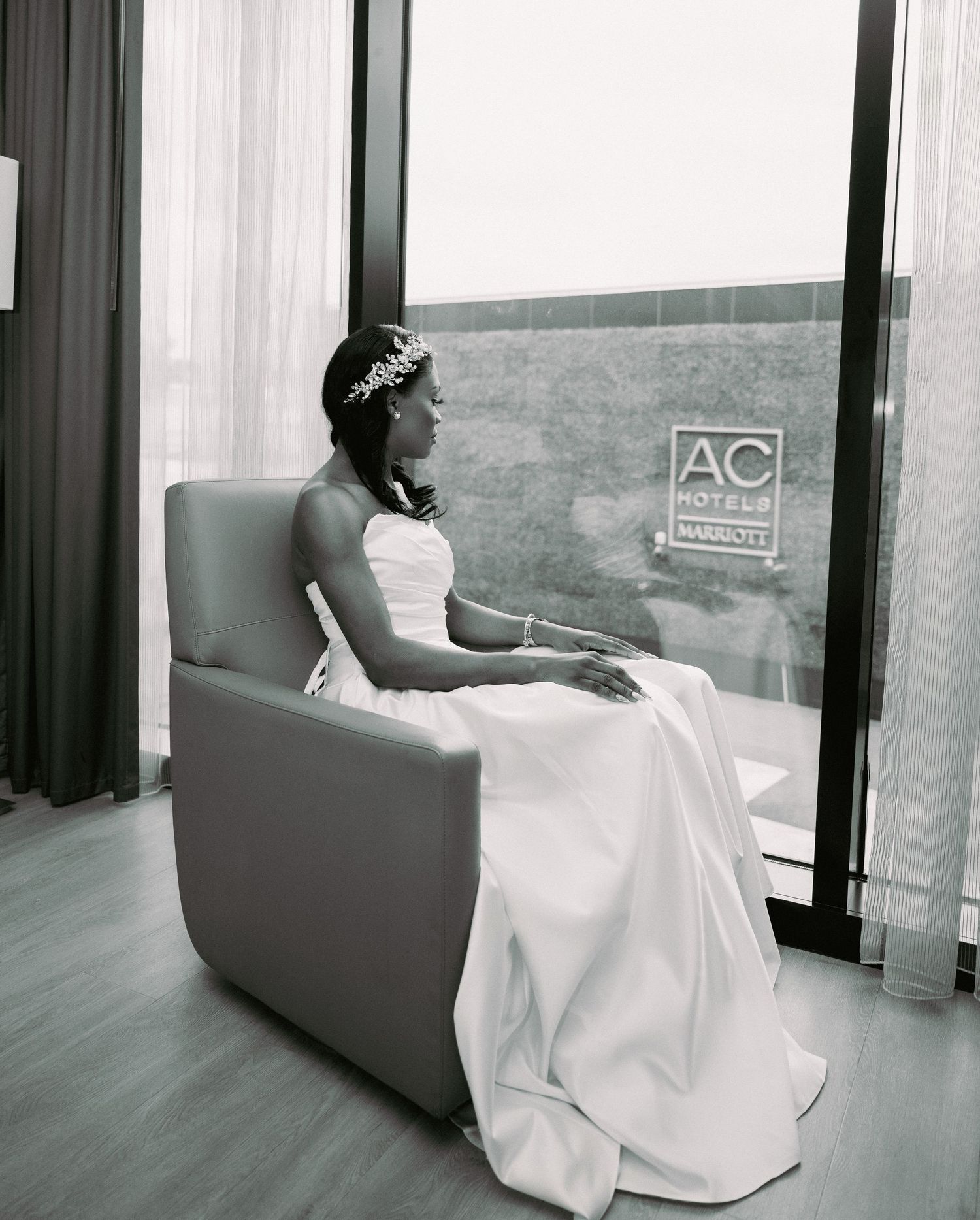 Wedding portrait in black and white showing bride resting on modern couch by window.