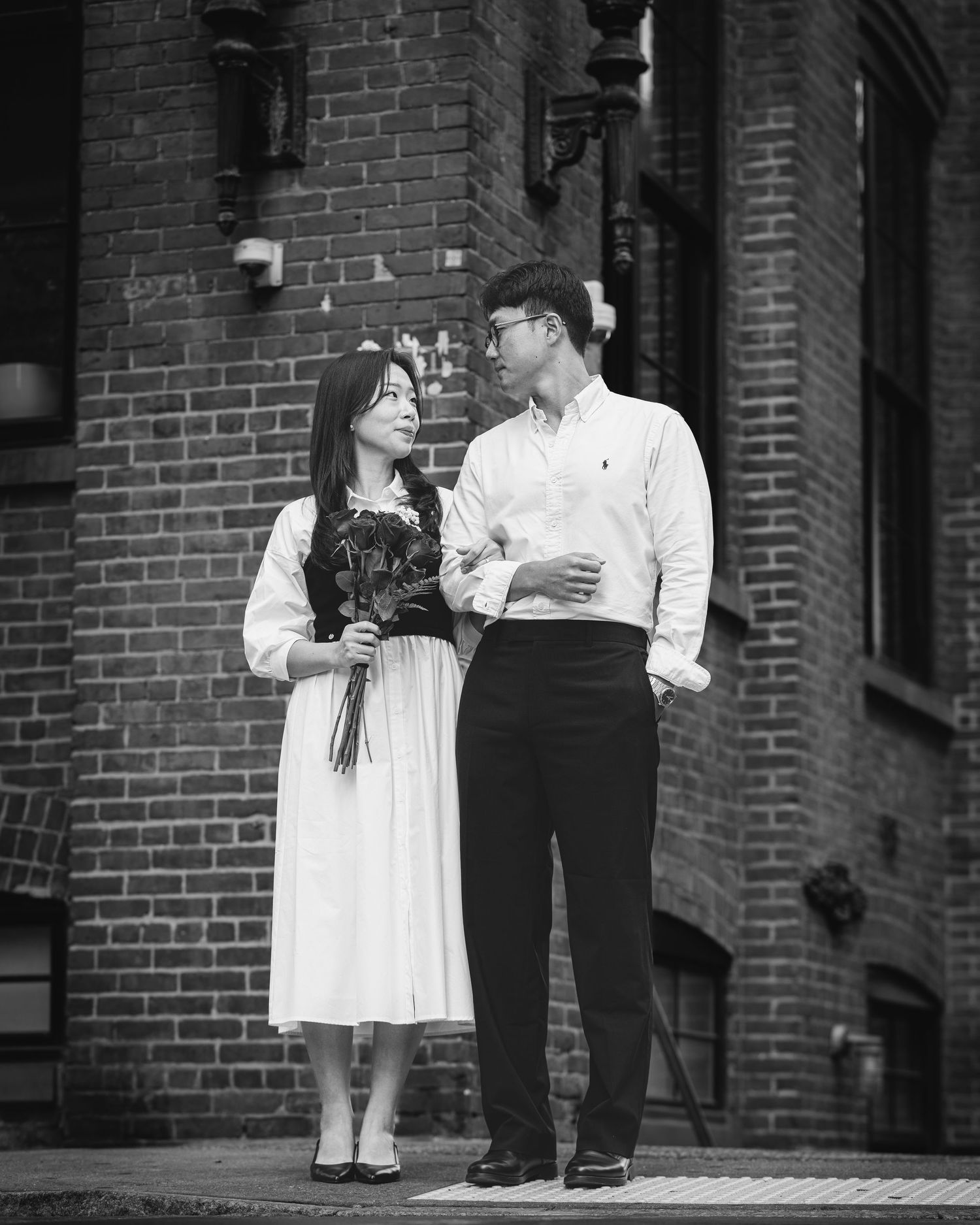Sweet engagement photos showing a couple walking and embracing near brick buildings.