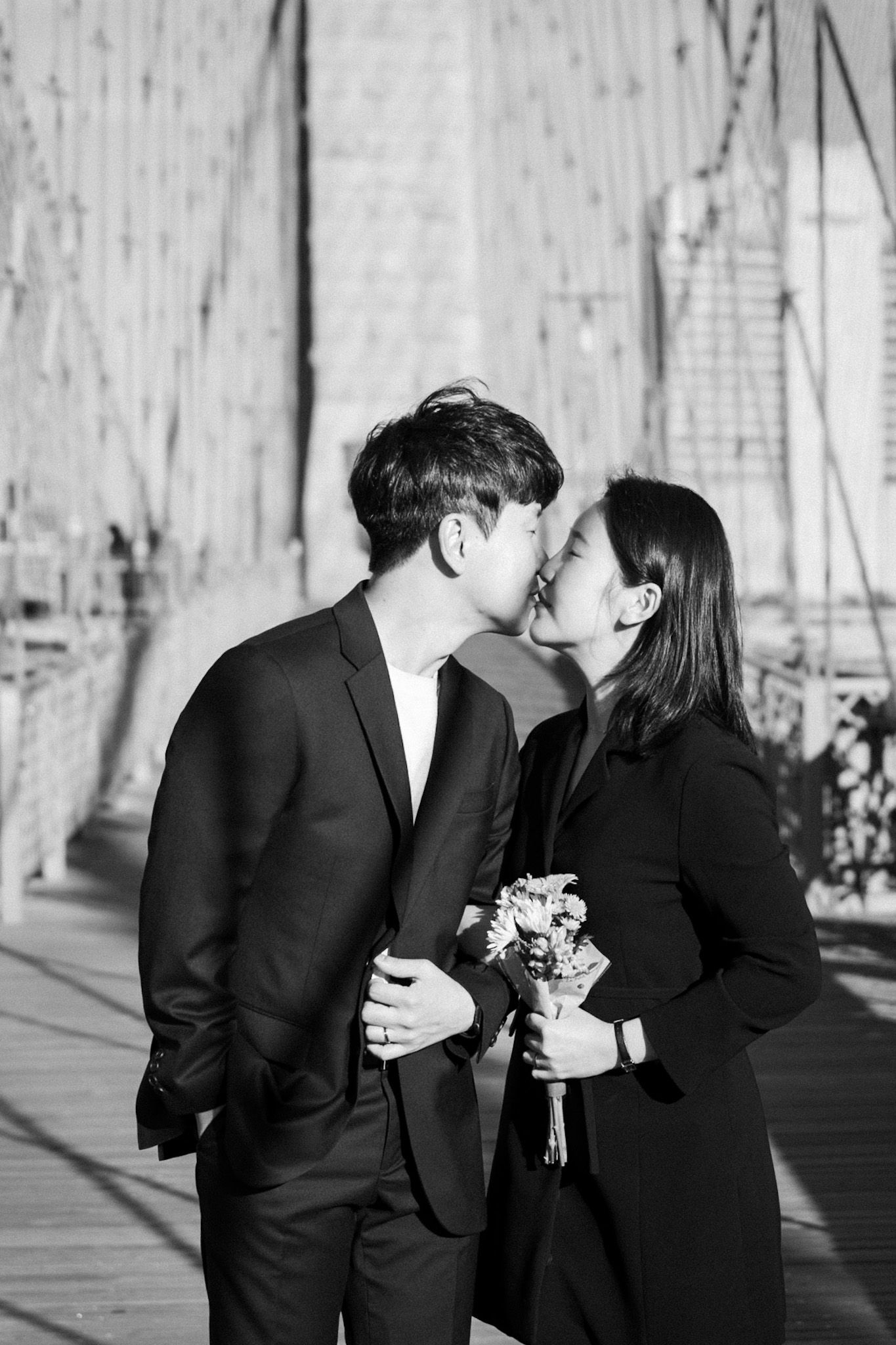 Couple in black formal attire share intimate moment during outdoor photo session.