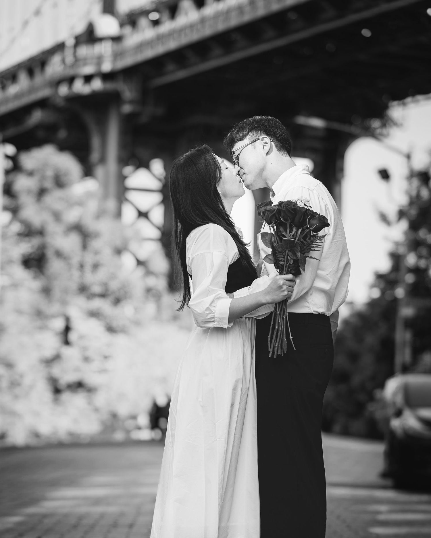 Artistic black and white engagement series showing intimate moments under a bridge.