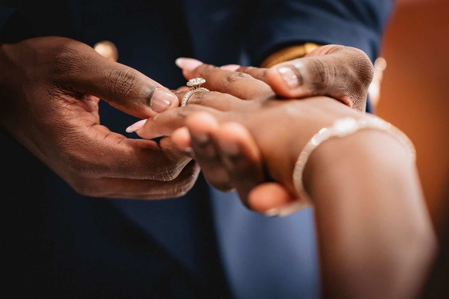 Close-up detail of hands exchanging wedding rings during an intimate ceremony.