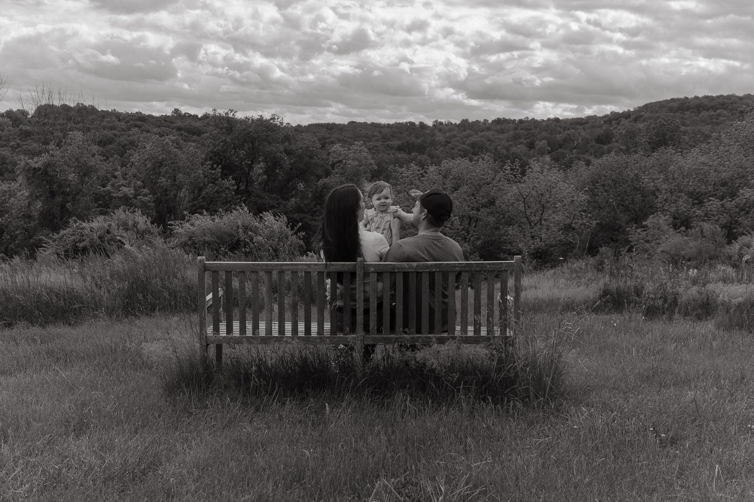 young family sitting on a bench overlooking the valley