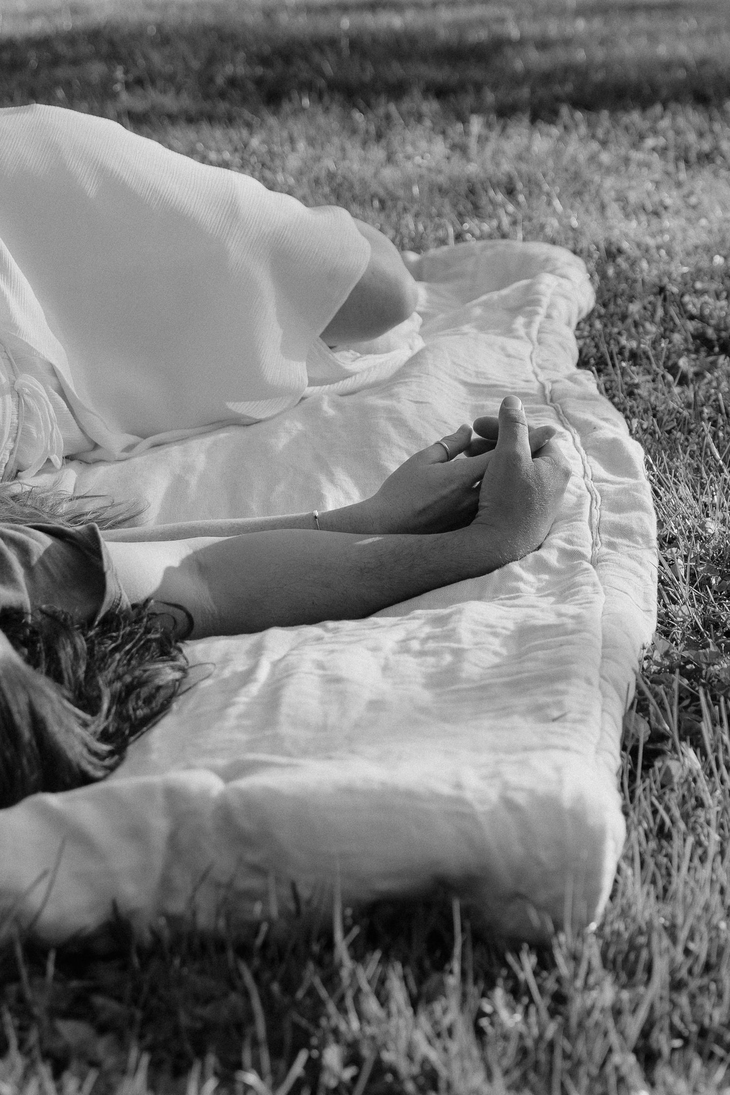 couple laying in the grass holding hands, close up shot of the hands